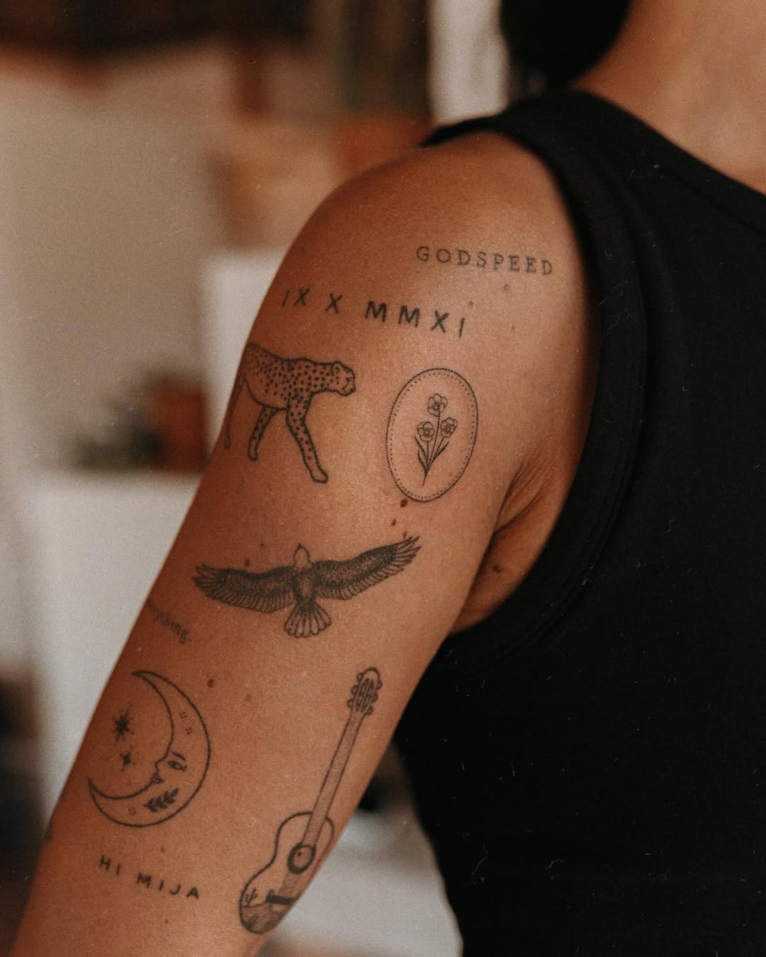 Cheetah, eagle, moon, guitar, flowers, lettering minimalist tattoo on the upper arm by Grace Wise - Handpoke Tattoos