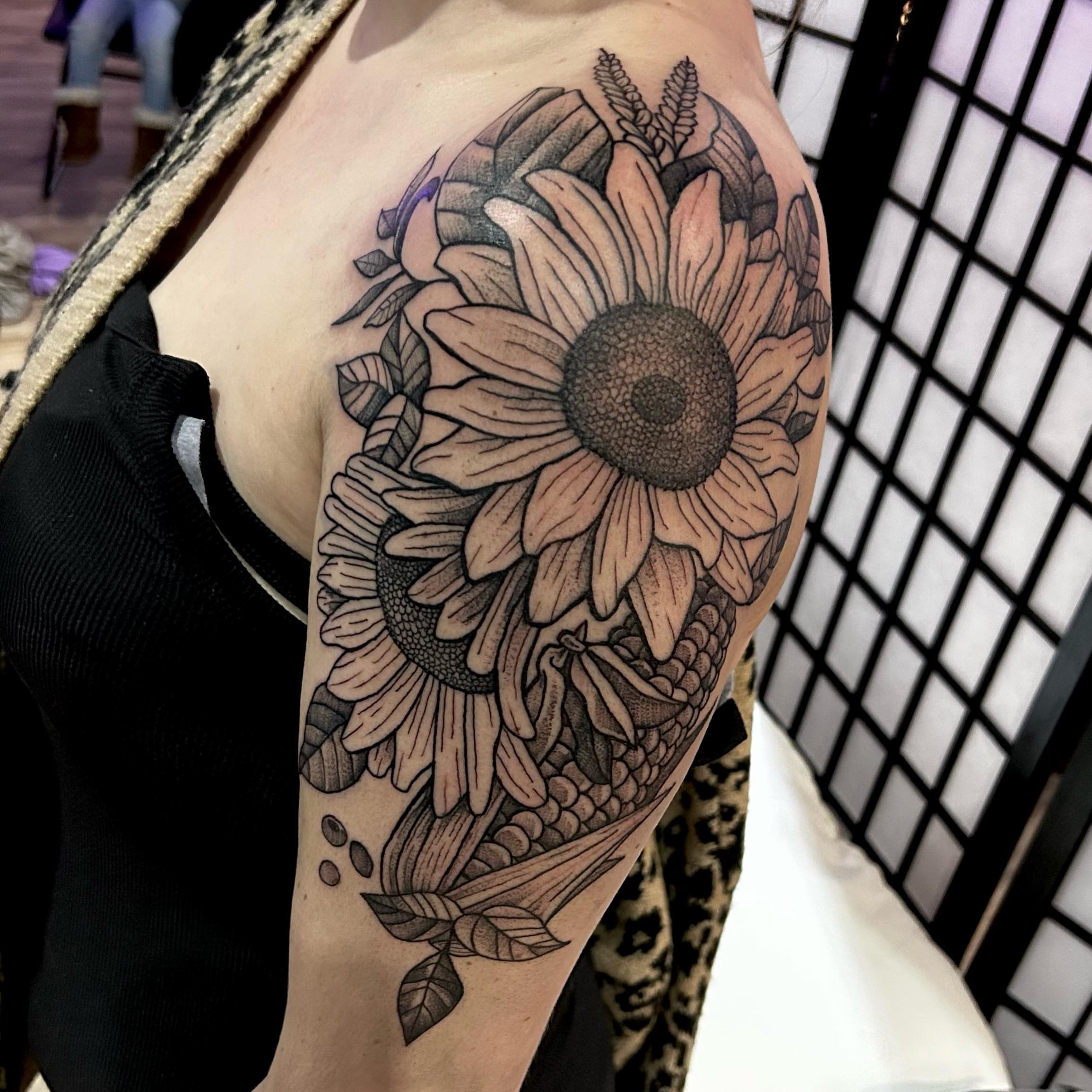 Sunflower black and grey tattoo on the upper arm by Cody Lambert