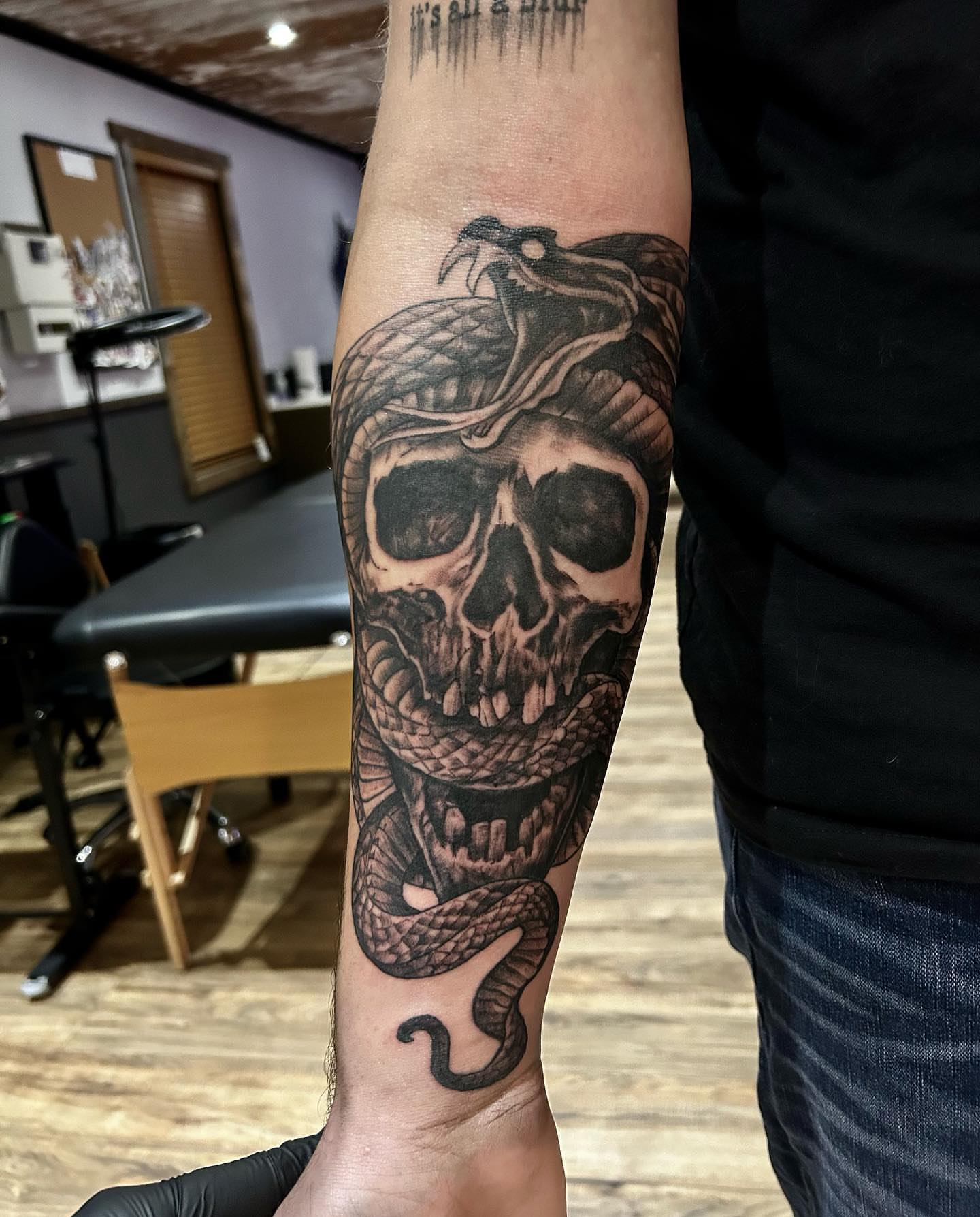 Skull with snake realism tattoo on the forearm by Cody Lambert