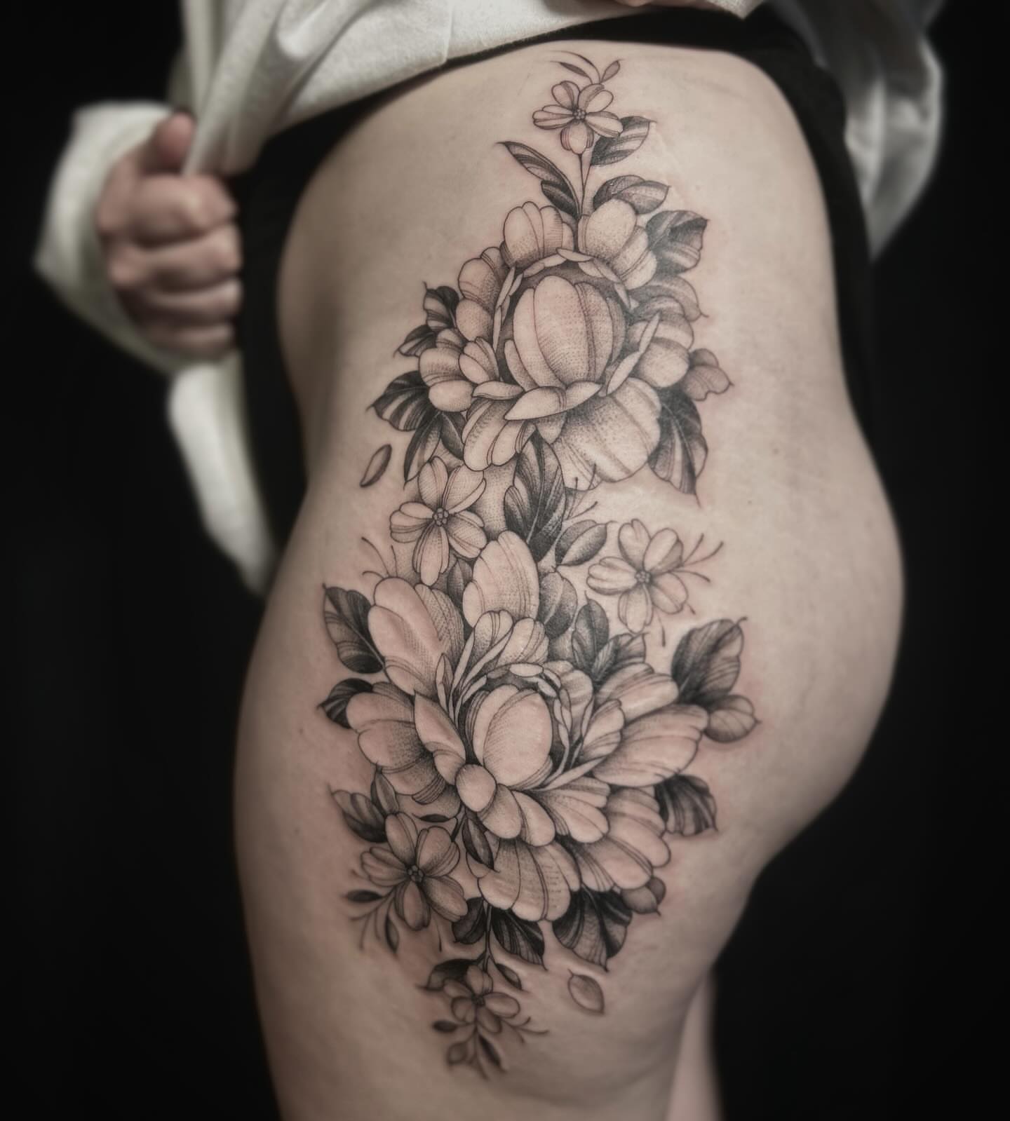Floral bouquet black and grey tattoo on the thigh by Lena Lawrence
