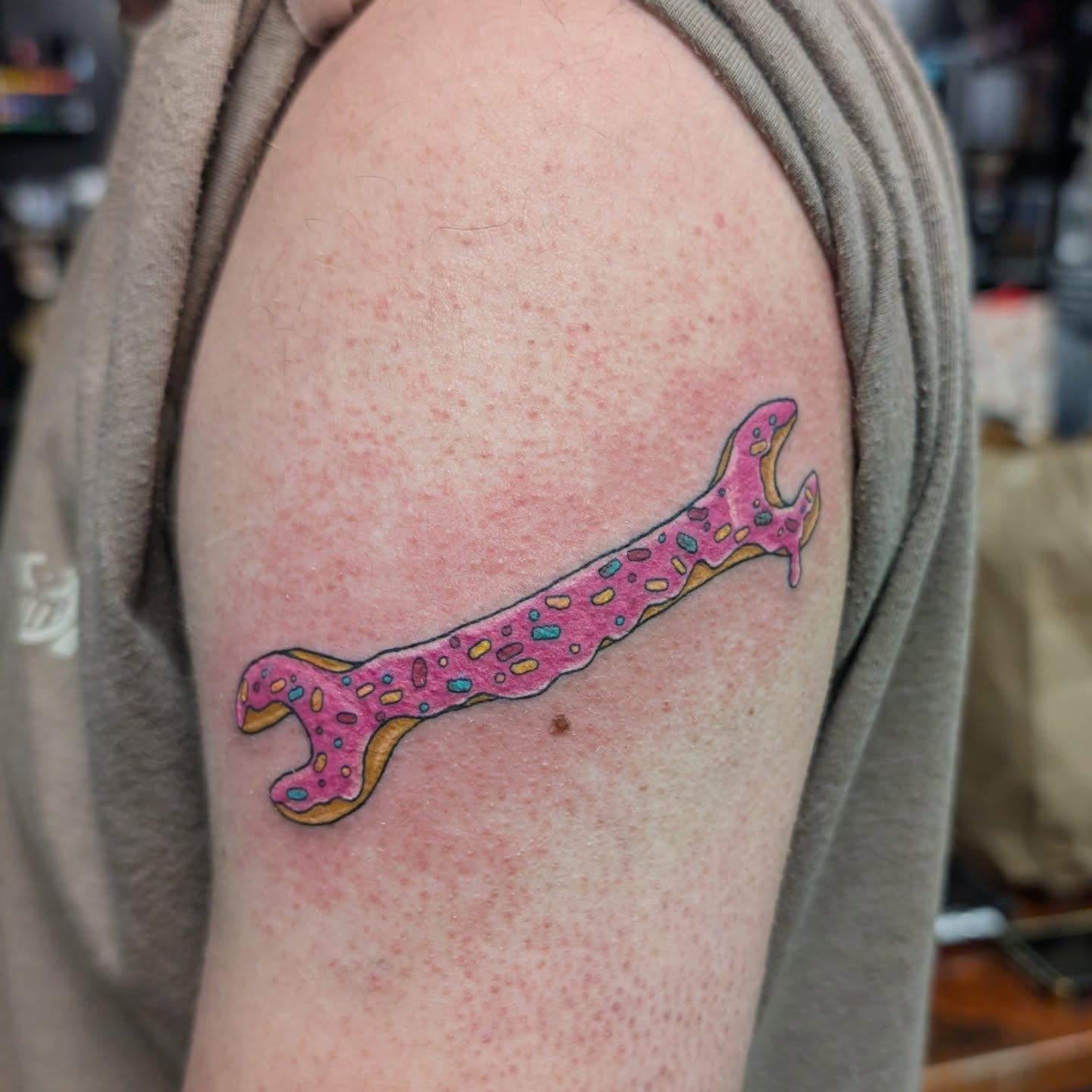 Donut-shaped wrench new school tattoo on the shoulder by Kara Falcon