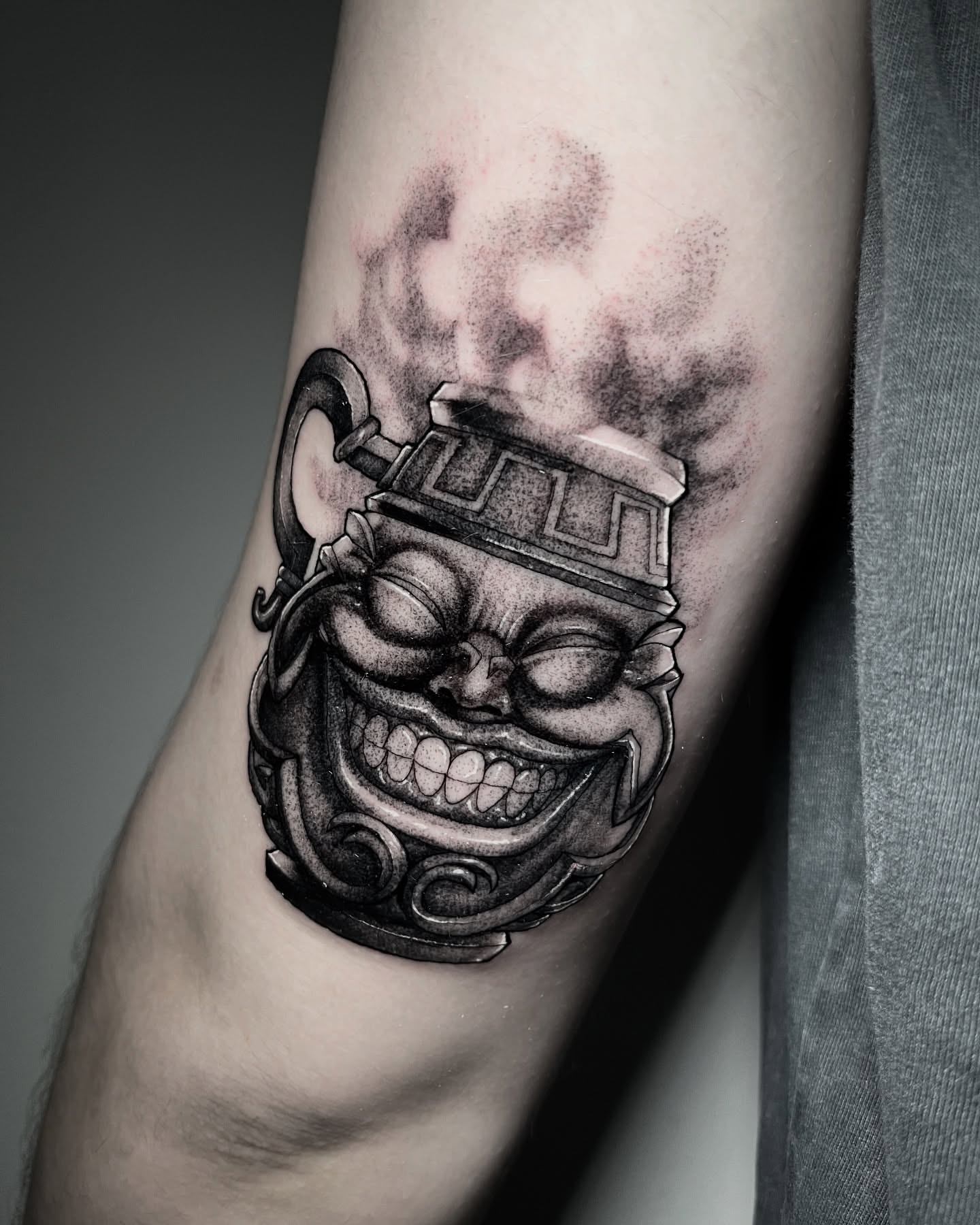Smiling mask black and grey tattoo on the forearm by Xavi Xiva TATTOO