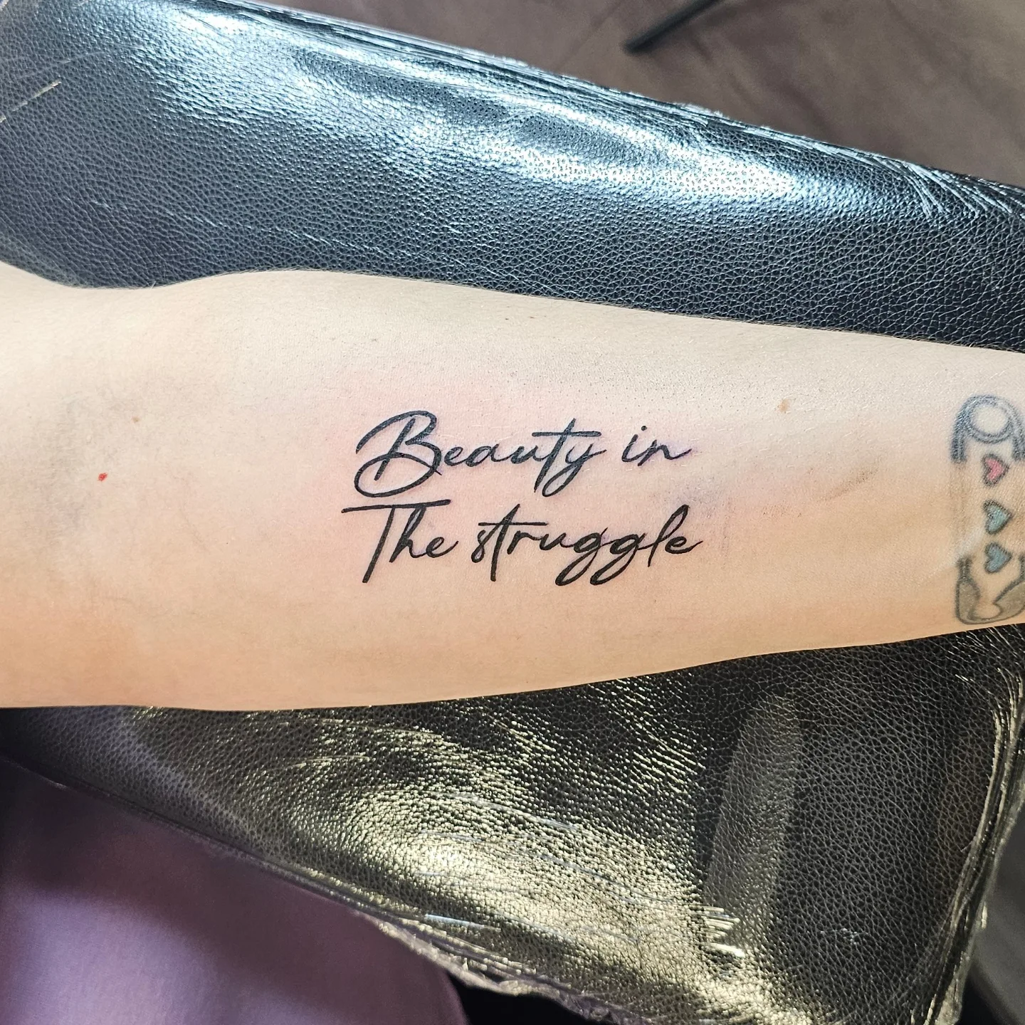 Beauty in The struggle lettering script tattoo on the forearm by John Briceño, Columbus, Ohio