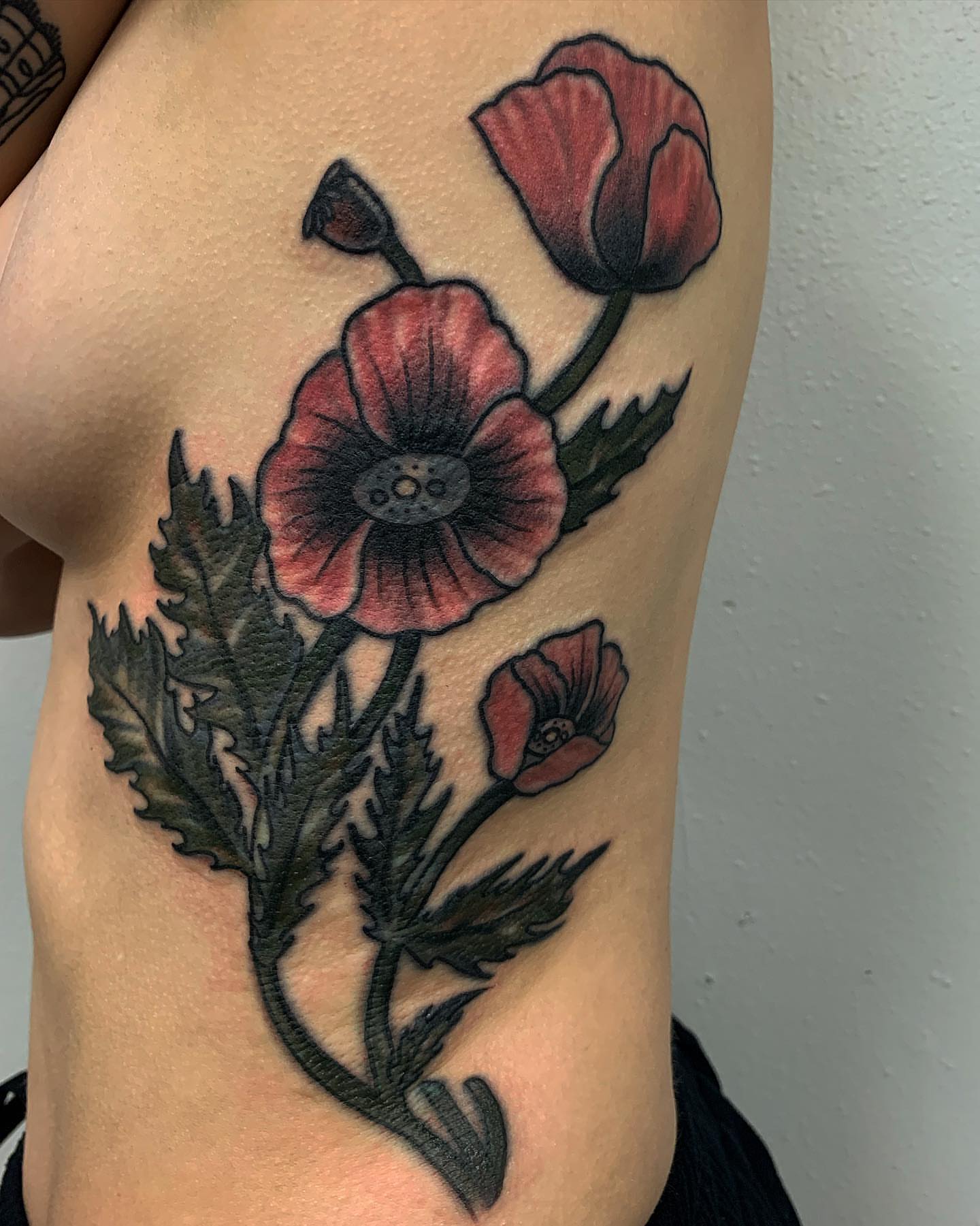 Poppy flowers American traditional tattoo on the ribs by Brii Moser