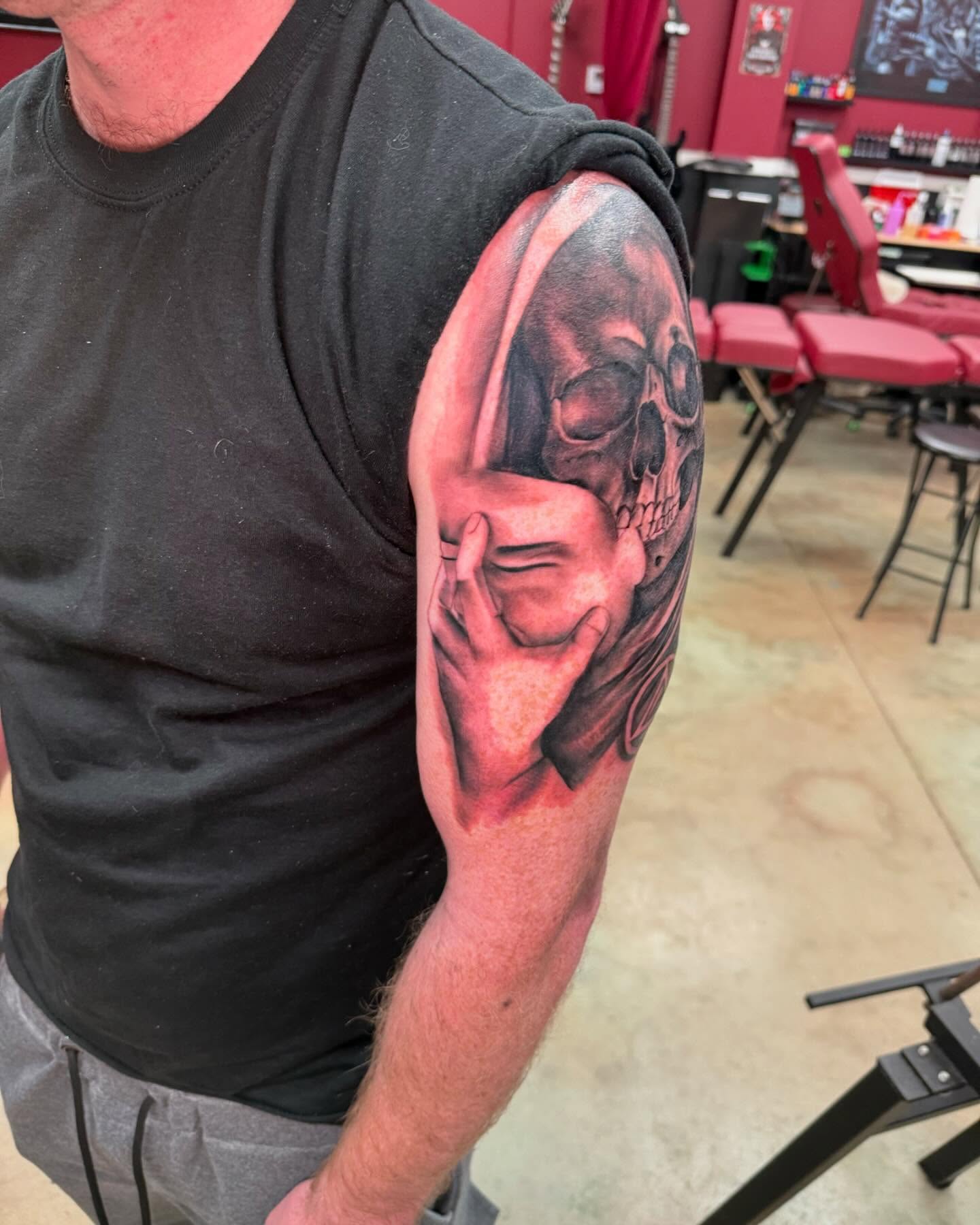 Skull and hand realism tattoo on the upper arm by Shawn Cook