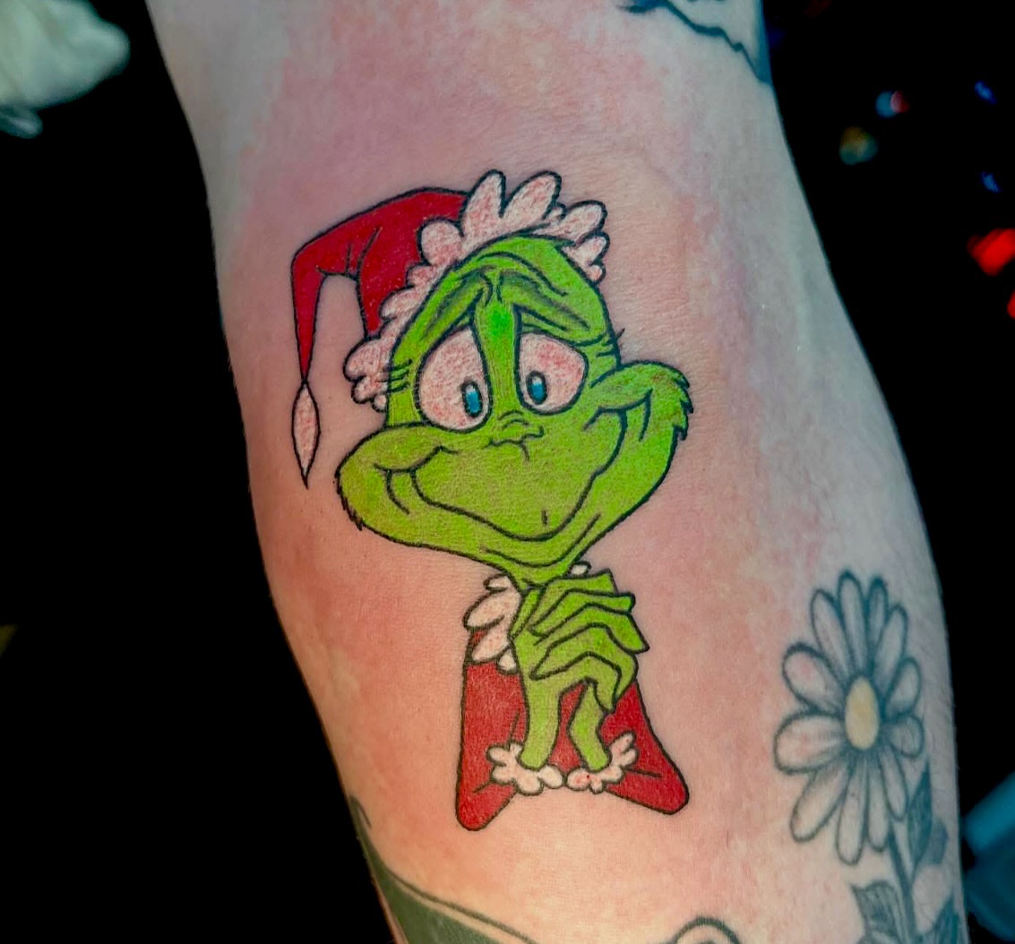 The grinch illustrative tattoo on the forearm by Kenny Buck