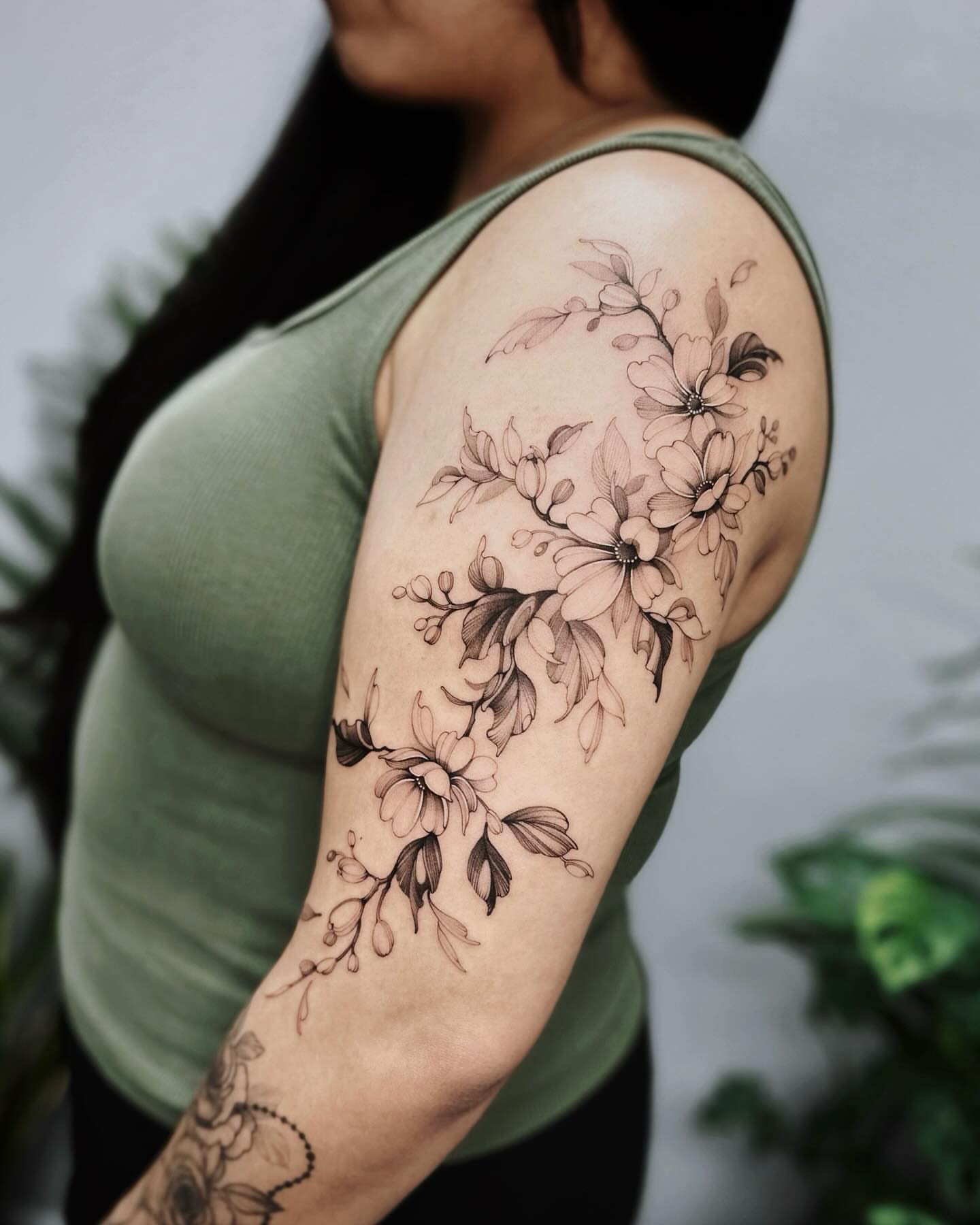 Floral bouquet black and grey tattoo on the upper arm by Angel