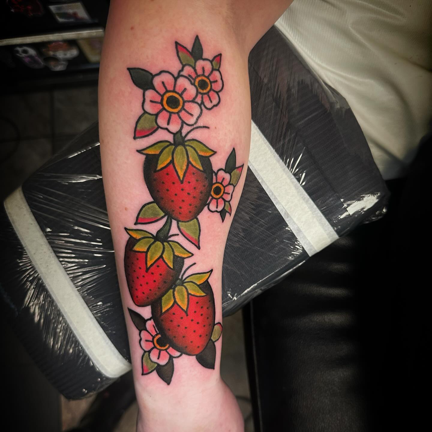 Strawberries and flowers American traditional tattoo on the forearm by Elizabeth Tabler