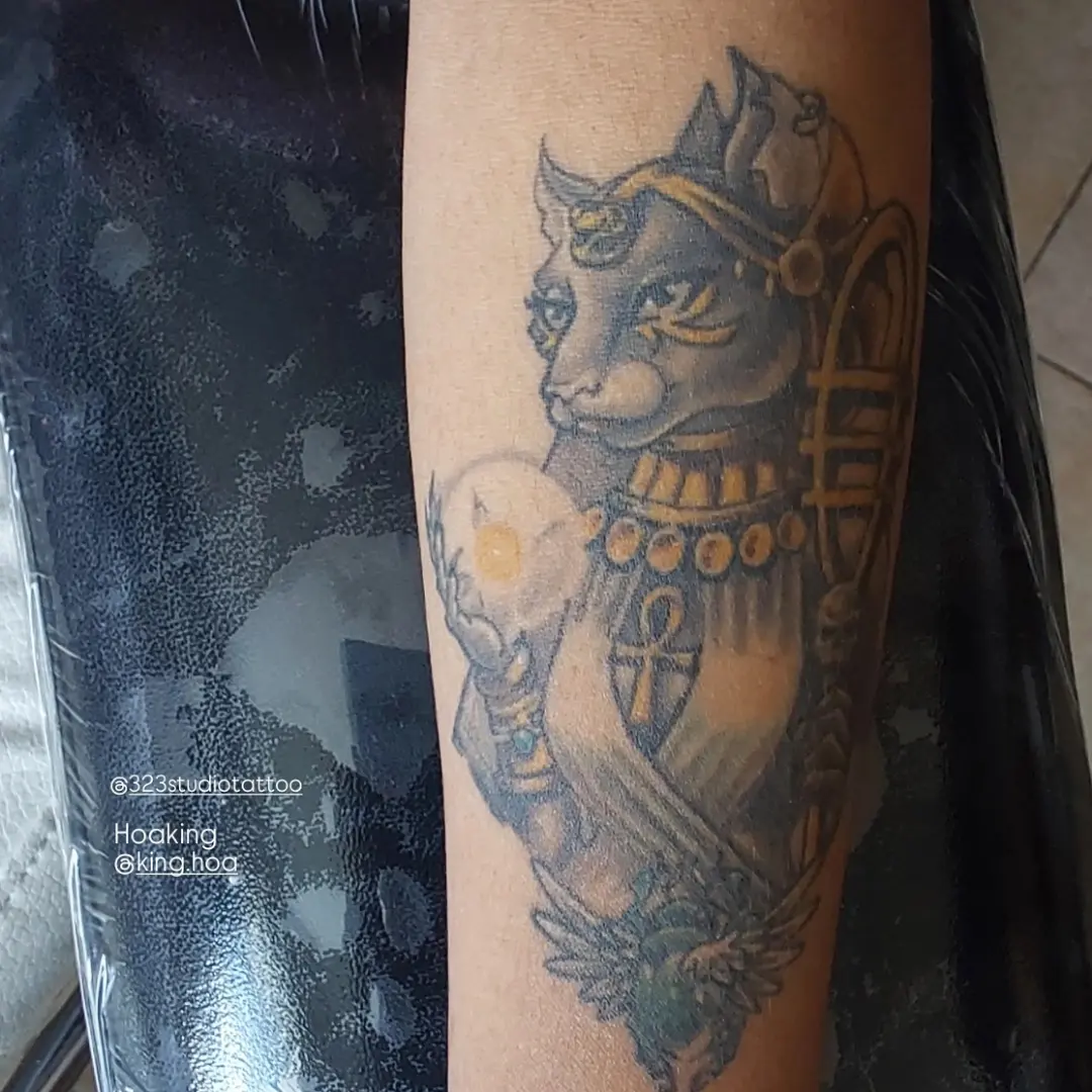 Cat deity black and grey tattoo on the forearm by Hoa King