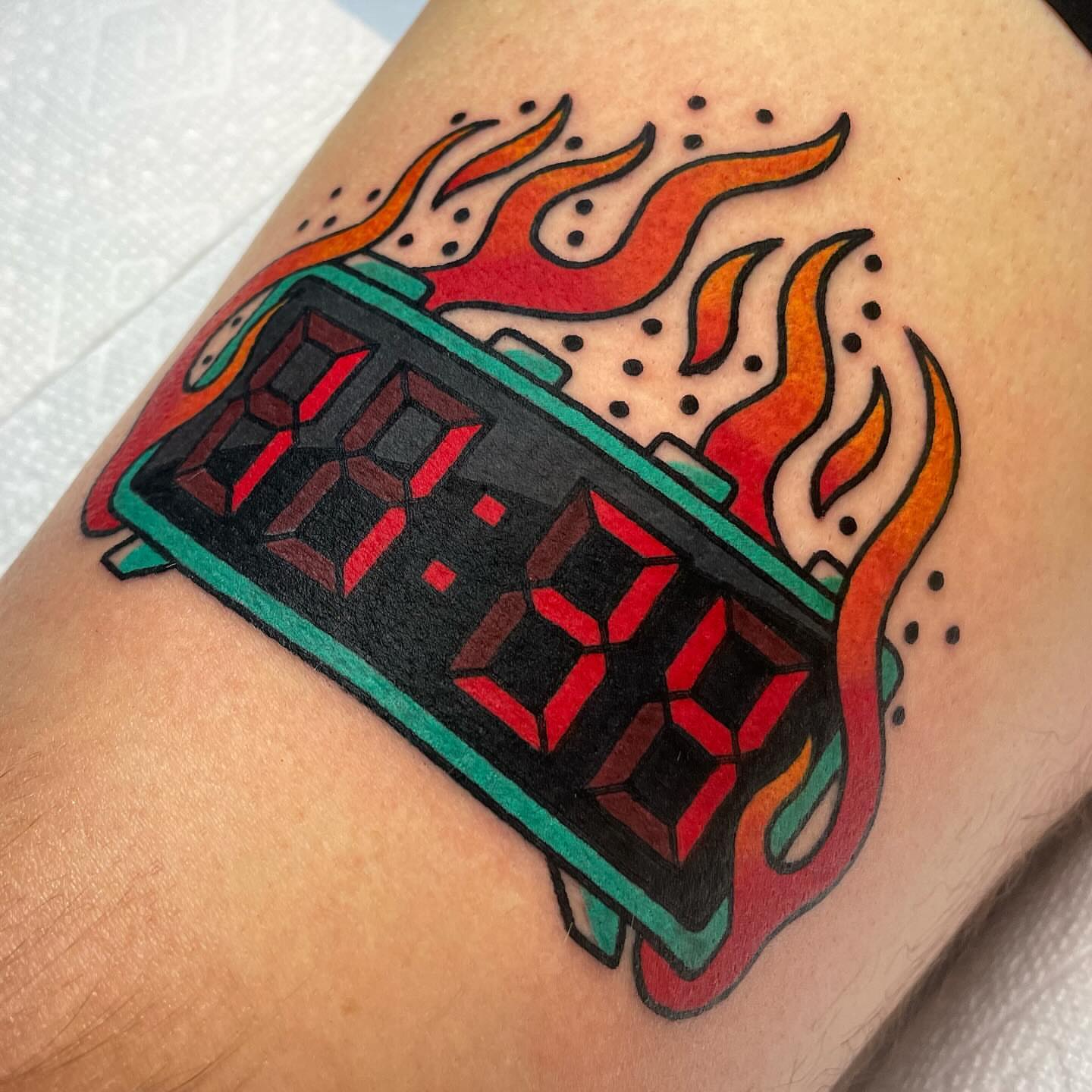 Digital clock with flames American traditional tattoo on the forearm by Nova Vaughn