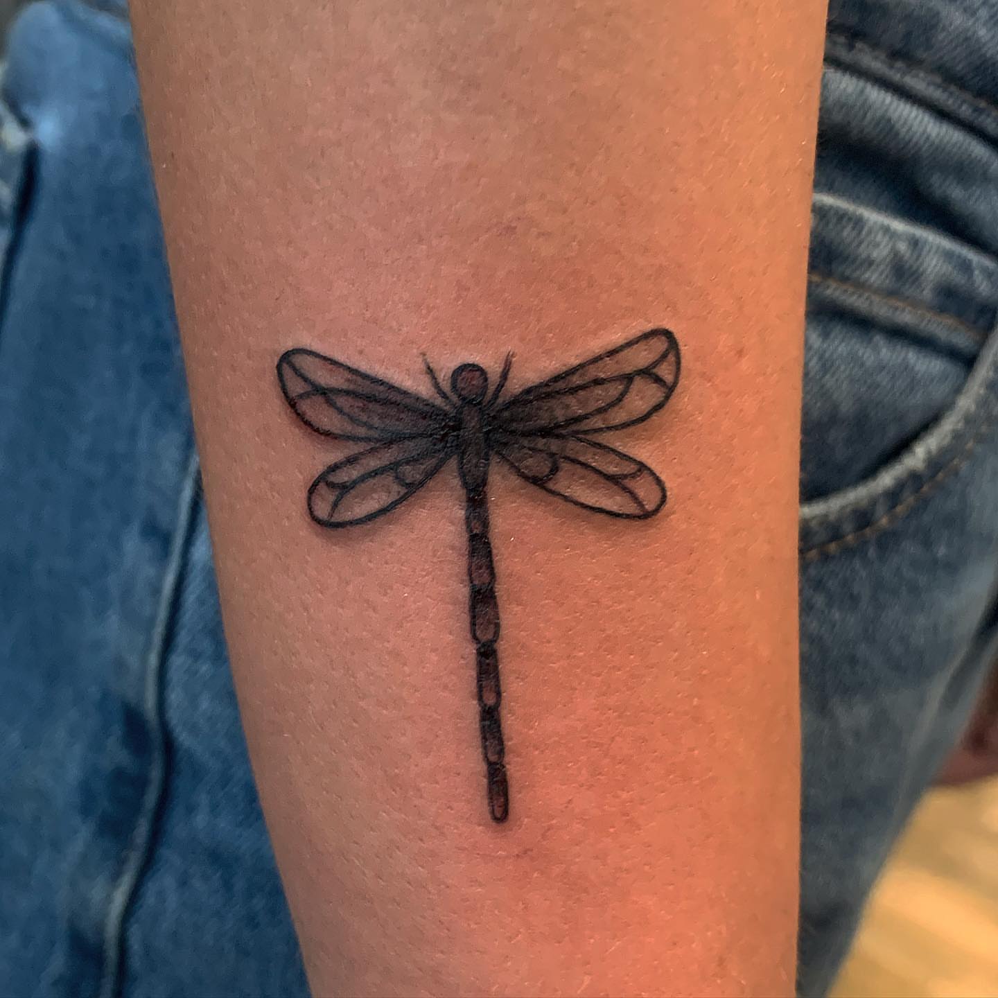 Dragonfly black and grey tattoo on the forearm by Brii Moser