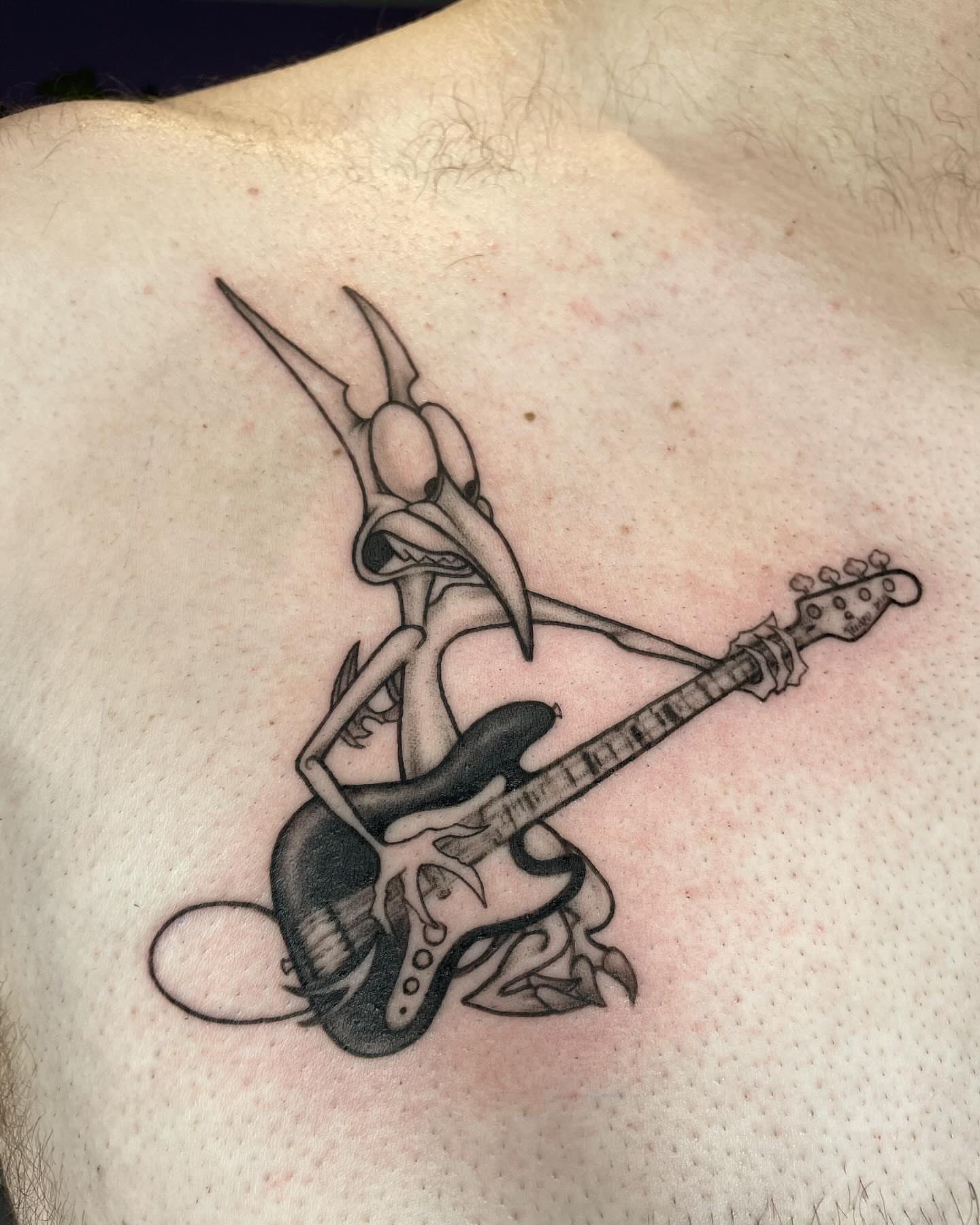 Road runner playing guitar black and grey tattoo on the chest by Christin Baumgart