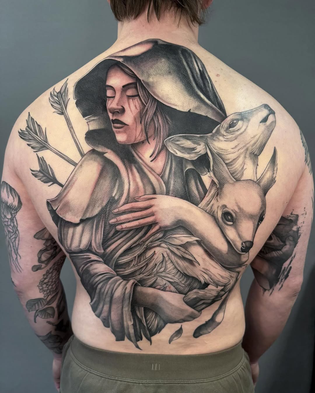 Woman holding a fawn realism tattoo on the back by Tattoo Artist