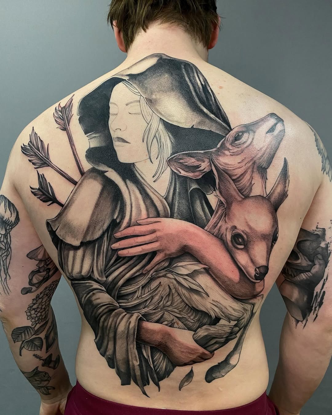 Woman holding a fawn realism tattoo on the back by Tattoo Artist