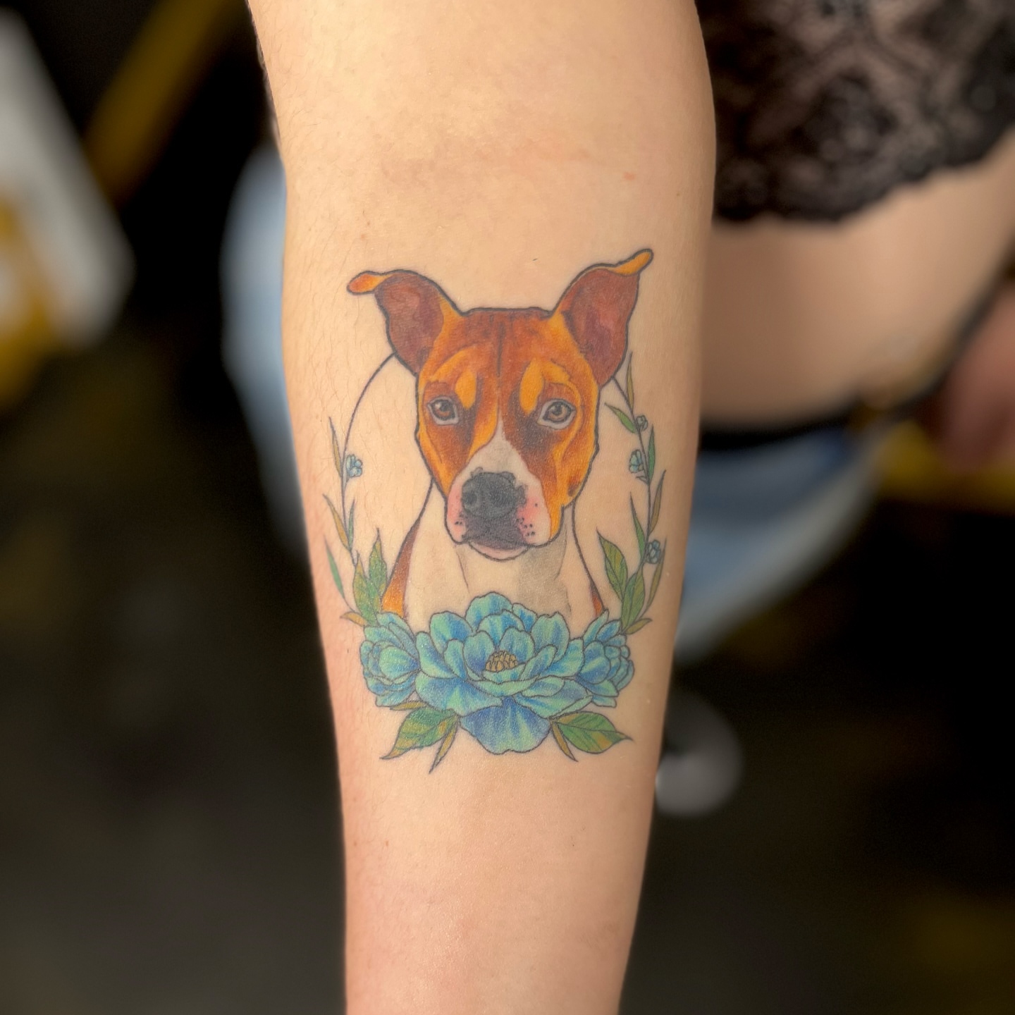 Dog with floral wreath realism tattoo on the forearm by Taylor Tha Color Queen