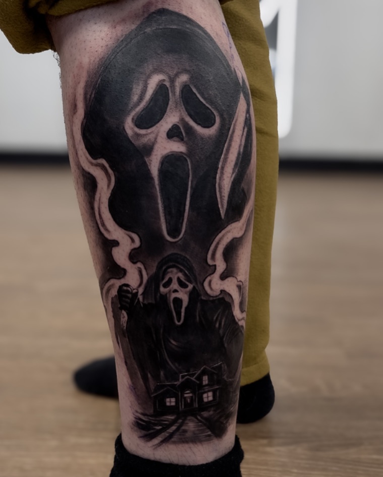 Scream mask black and grey tattoo on the calf by Andy