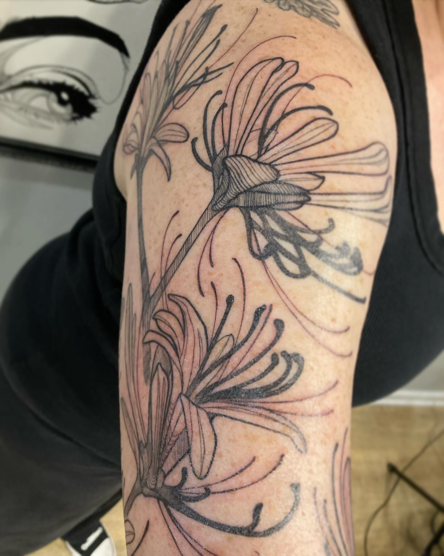 Lilies black and grey tattoo on the upper arm by Rizzie D'Alterio