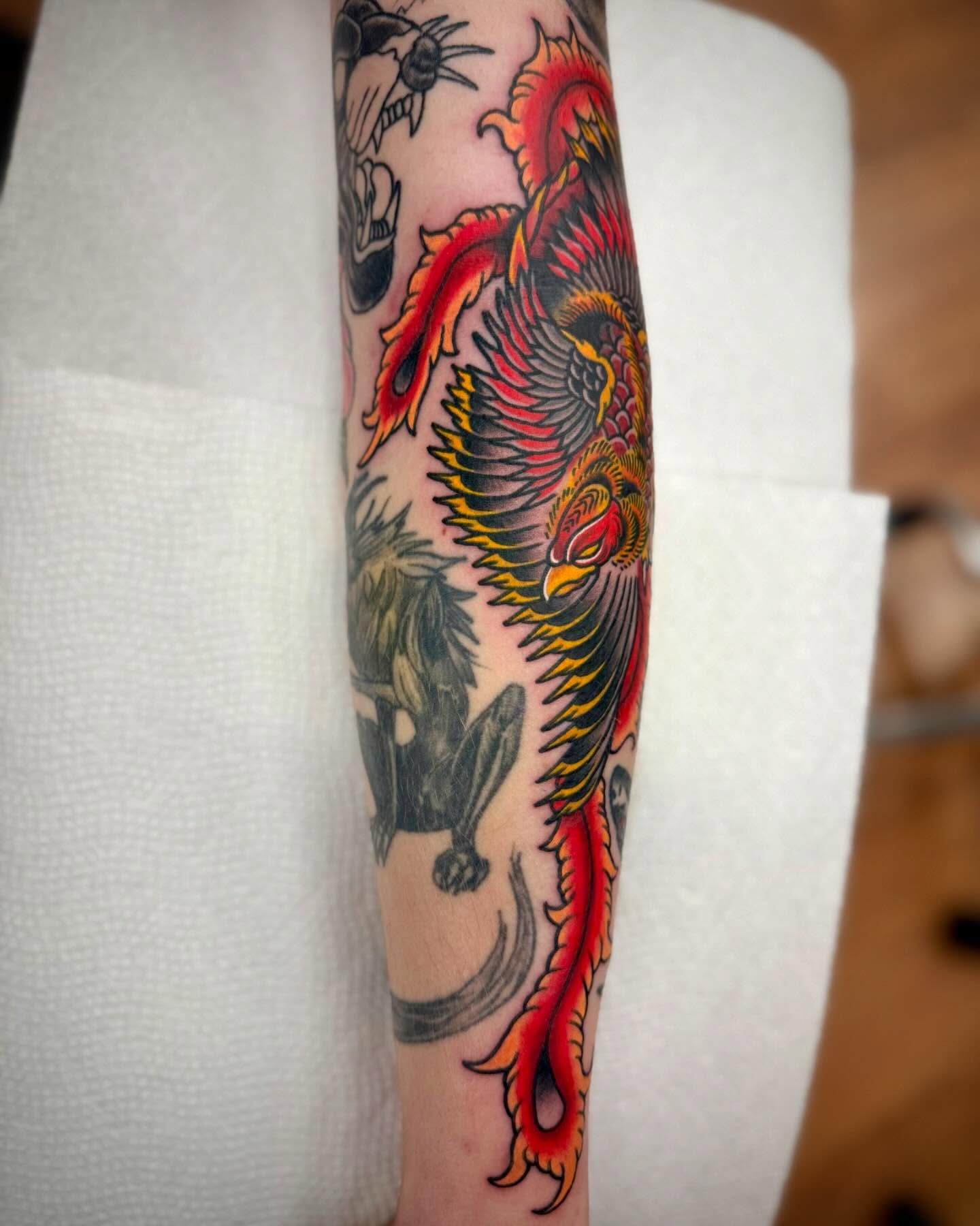 Phoenix American traditional tattoo on the forearm by Sam Babcock