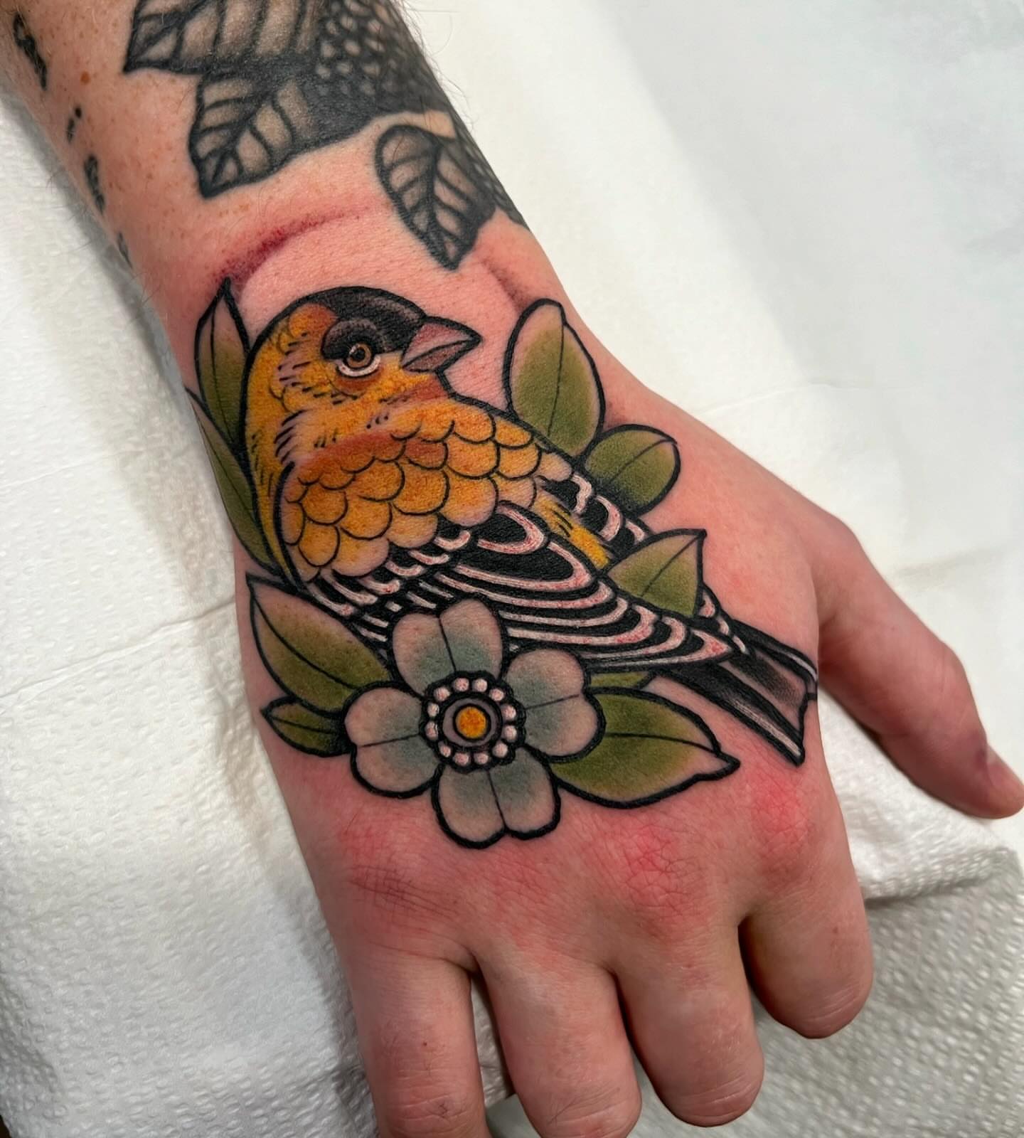 Bird and flower American traditional tattoo on the hand by Kyle Olson, Salt Lake City, Utah