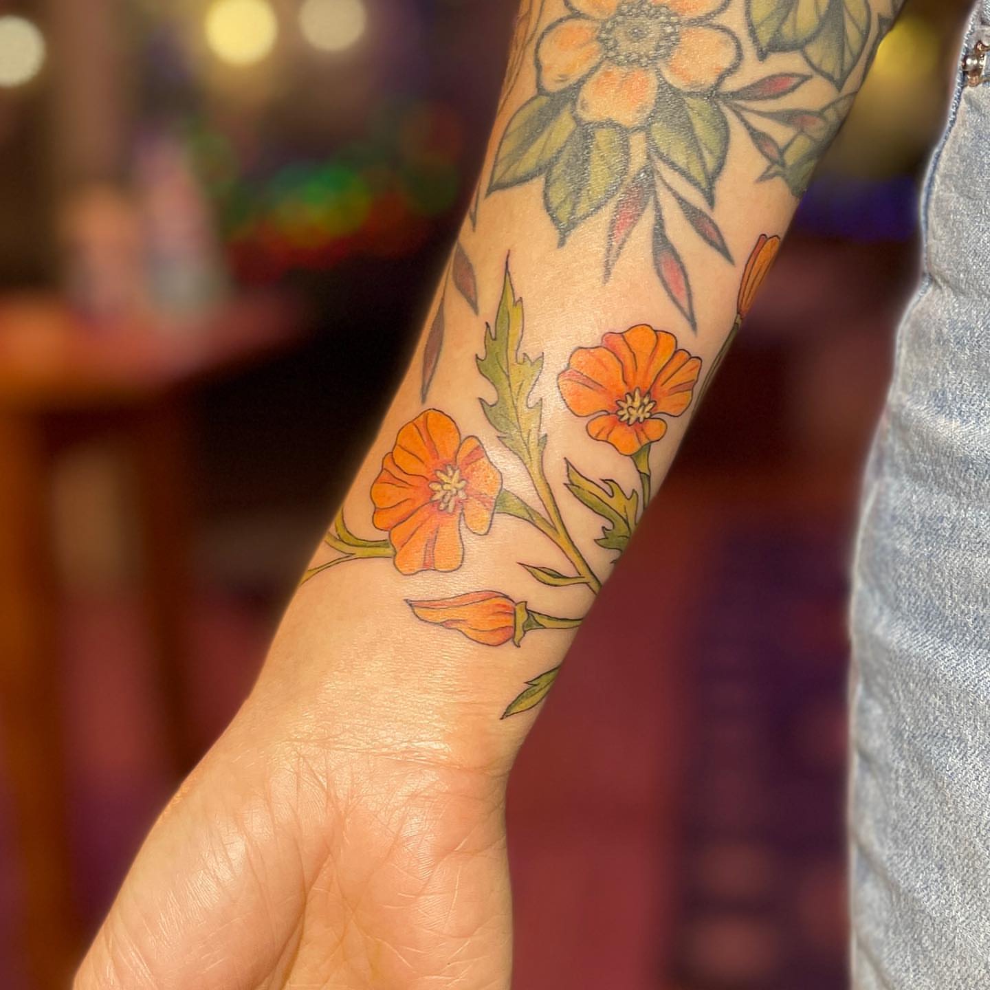 Orange poppies new school tattoo on the forearm by Reba Slate