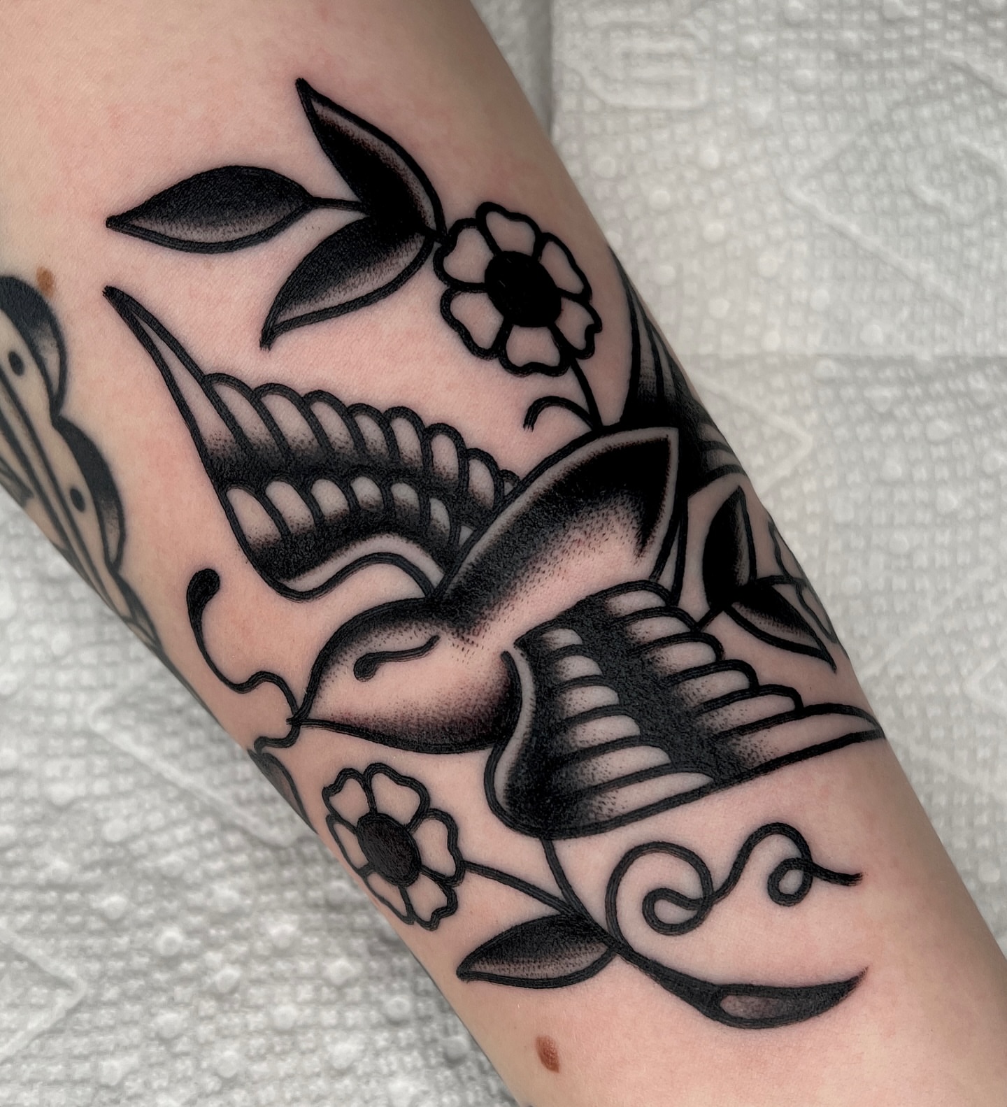 Bird and flowers black and grey tattoo on the forearm by Ian Jett