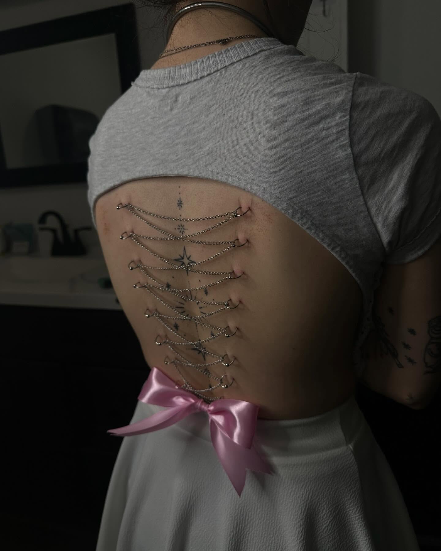 Chains and bow black and grey tattoo on the back by Zoie Stiles
