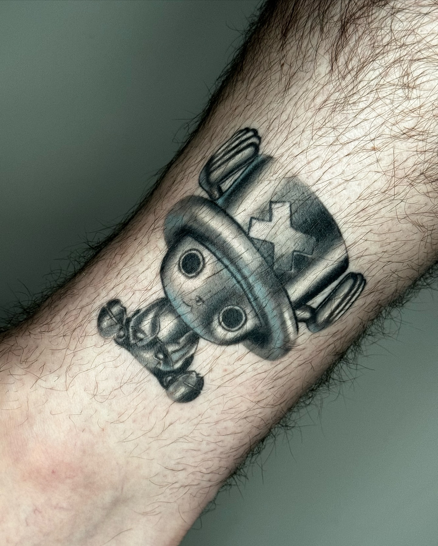 Robot black and grey tattoo on the forearm by Mel