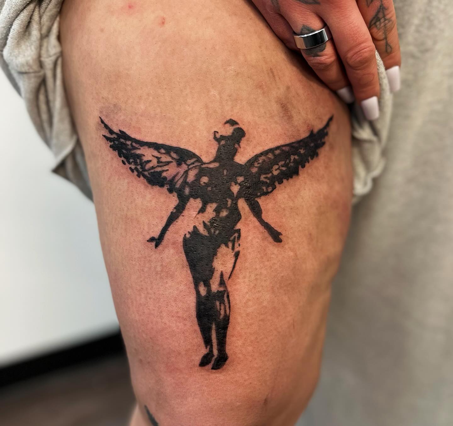 Winged figure black and grey tattoo on the thigh by πΎππ π π·ππ πππππ πΏπππππ π¬πππππ