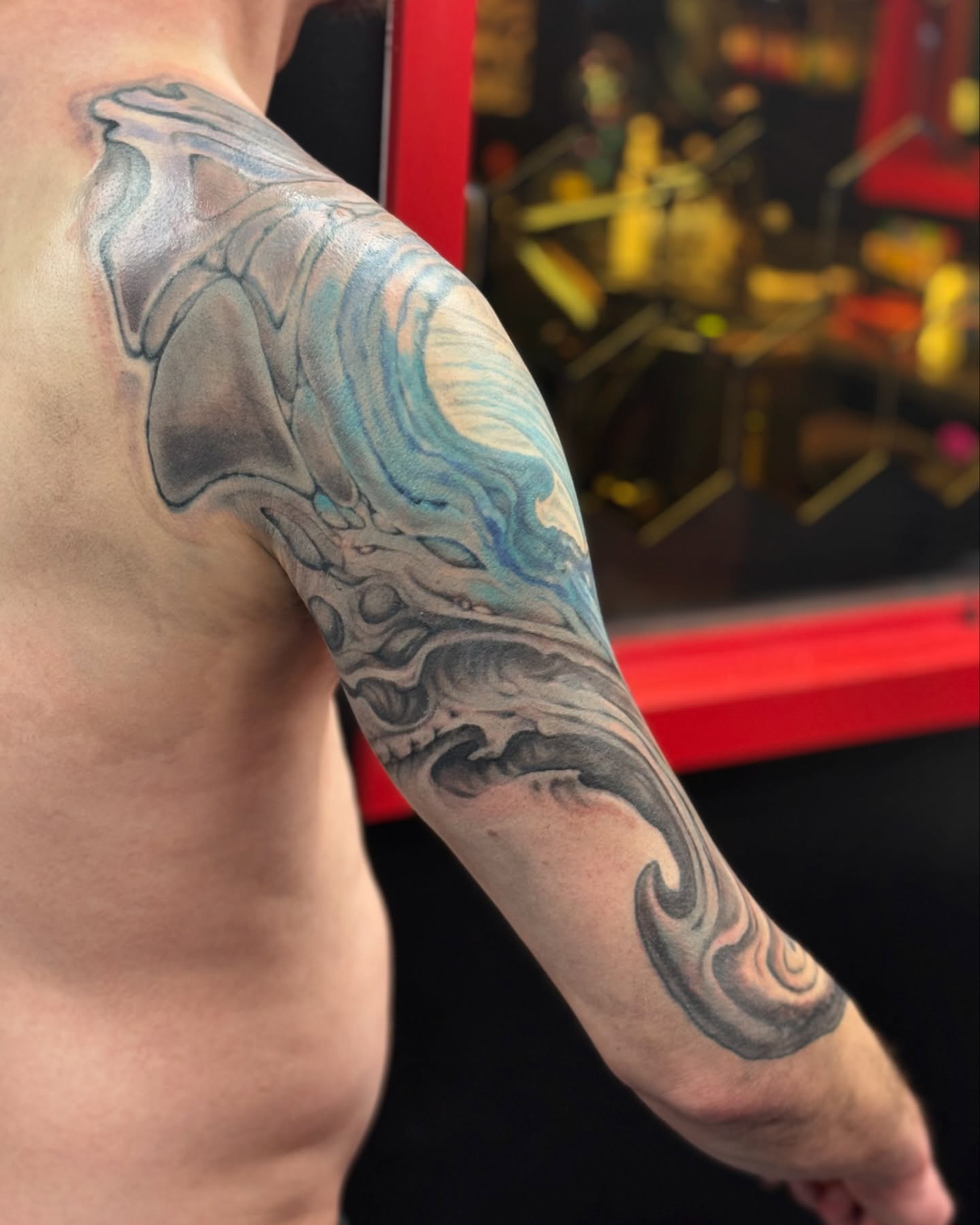 Wave black and grey tattoo on the upper arm by Jordan Rookus
