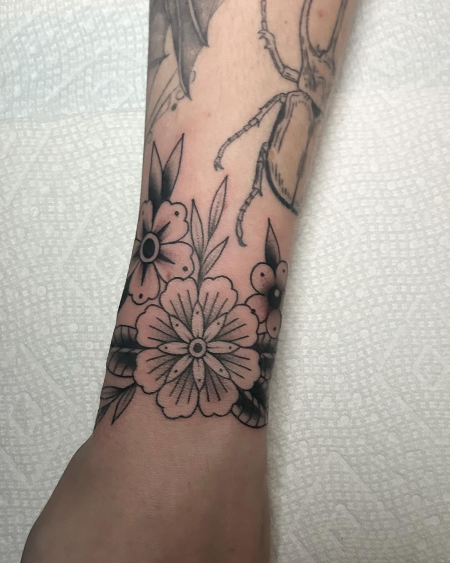 Flowers and beetle black and grey tattoo on the forearm by Kayla Shoffner