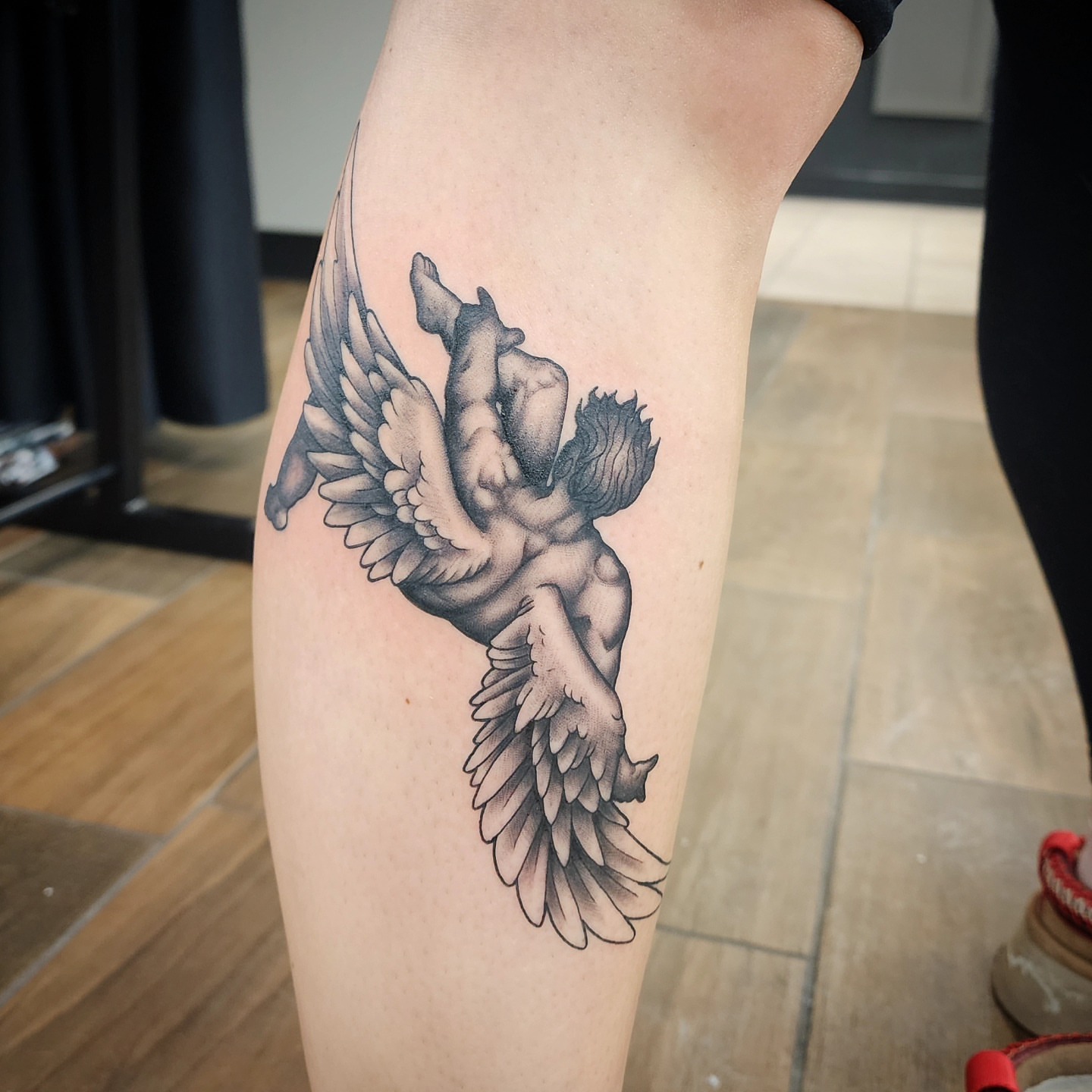 Winged figure realism tattoo on the thigh by bobby allensworth