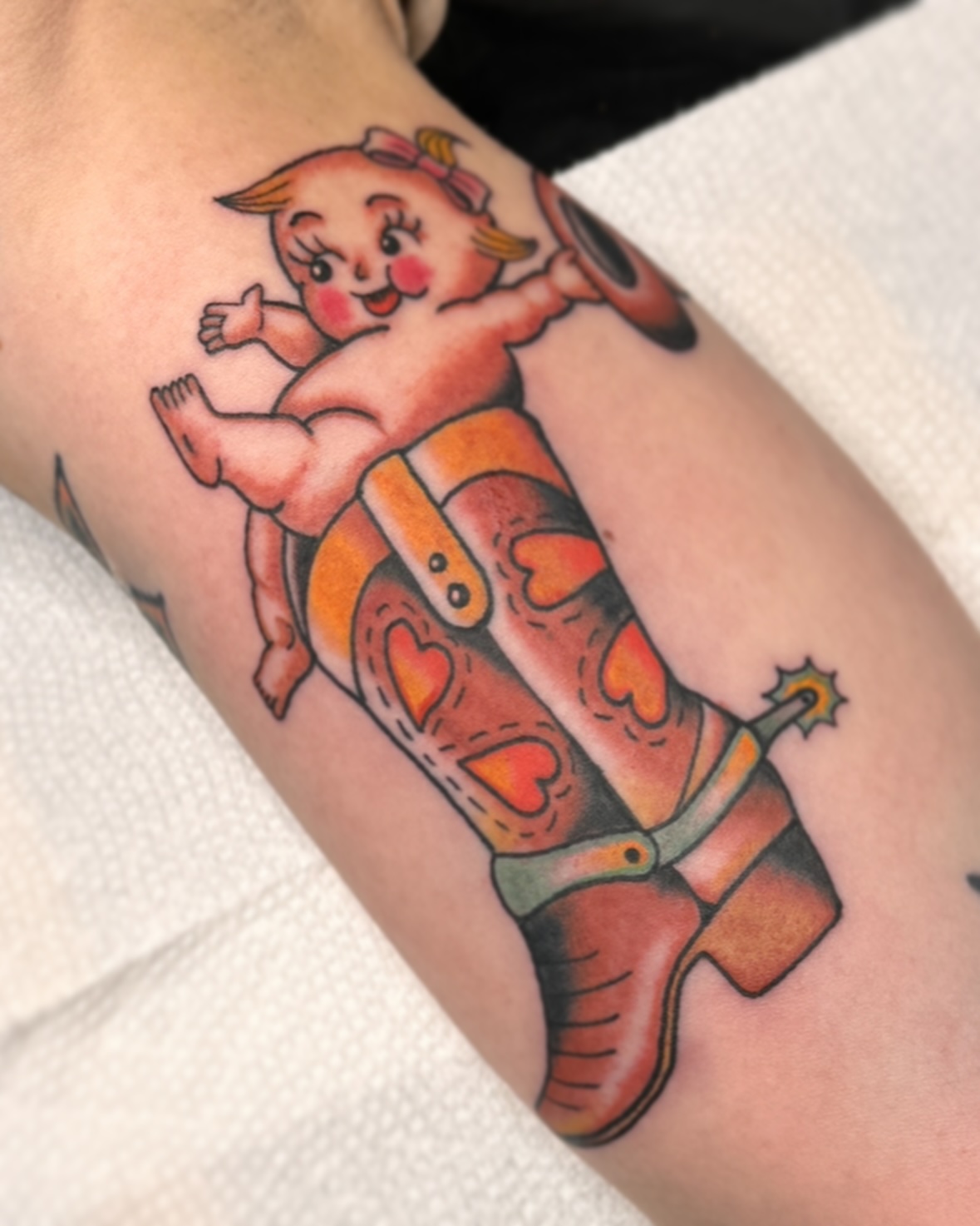 Baby in cowboy boot American traditional tattoo on the forearm by Drew McElveney, Austin, Texas