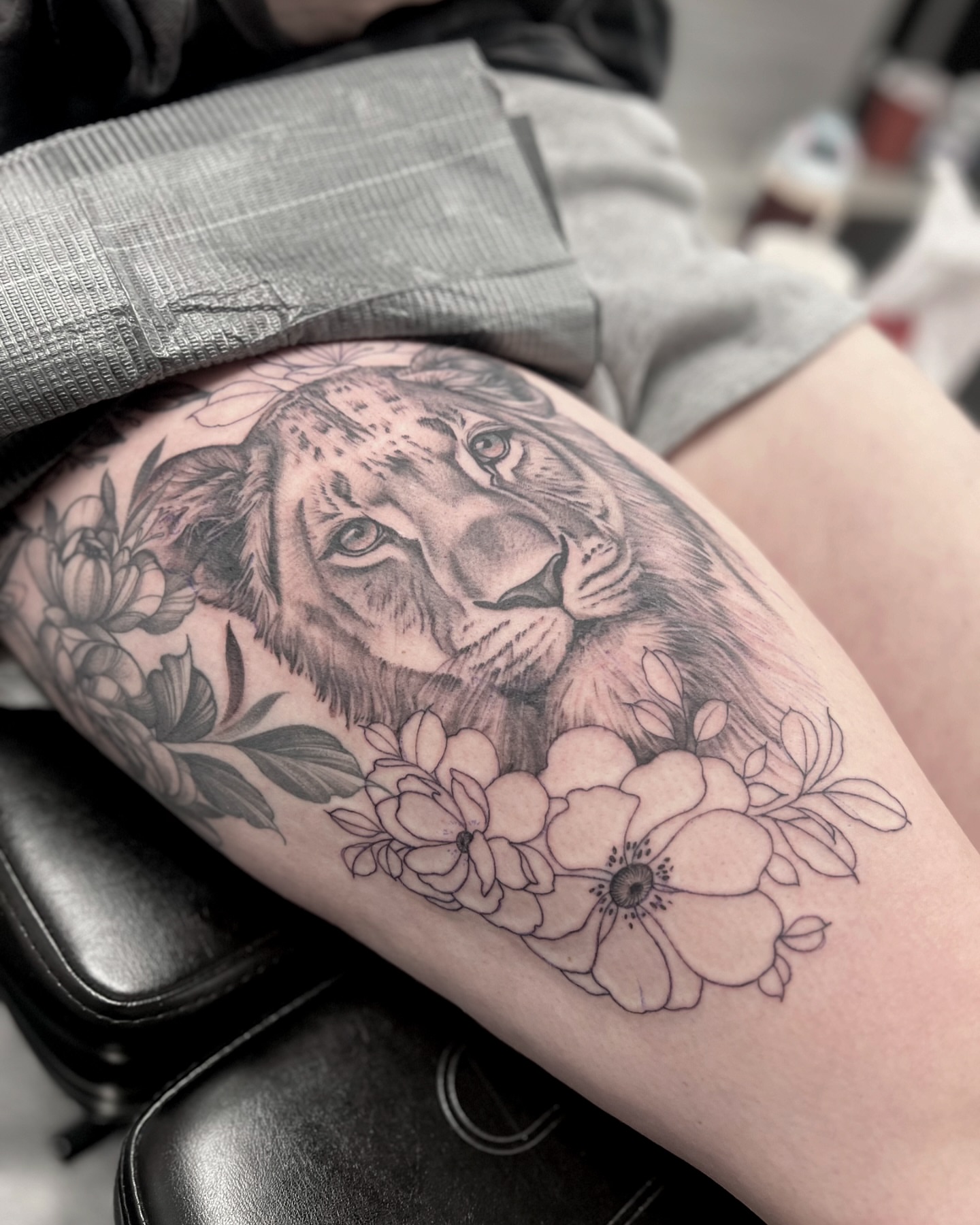 Lion with flowers realism tattoo on the thigh by Chelsea Speirs