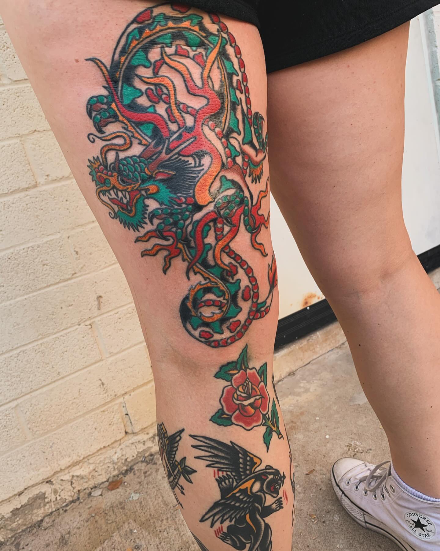 Dragon and rose American traditional tattoo on the thigh by Chrissie