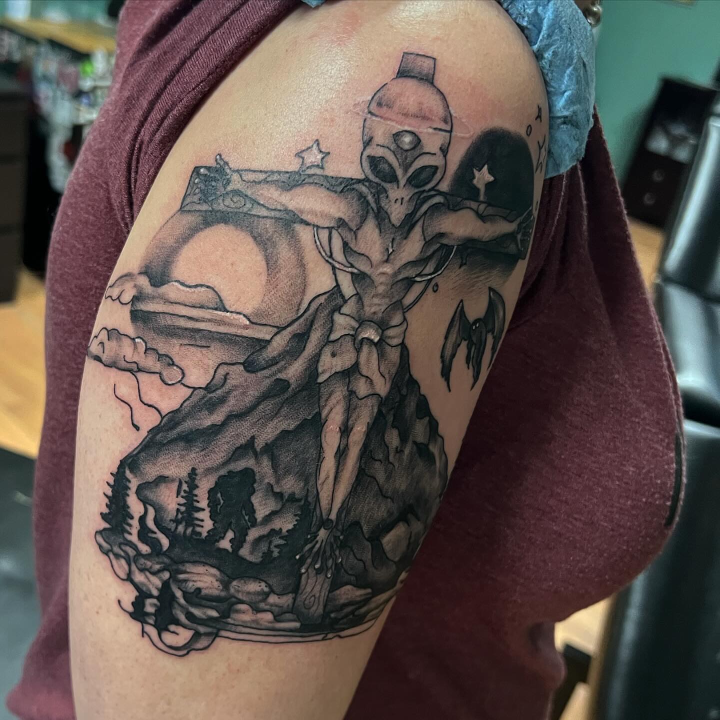 Alien figure black and grey tattoo on the shoulder by Katie Sayre
