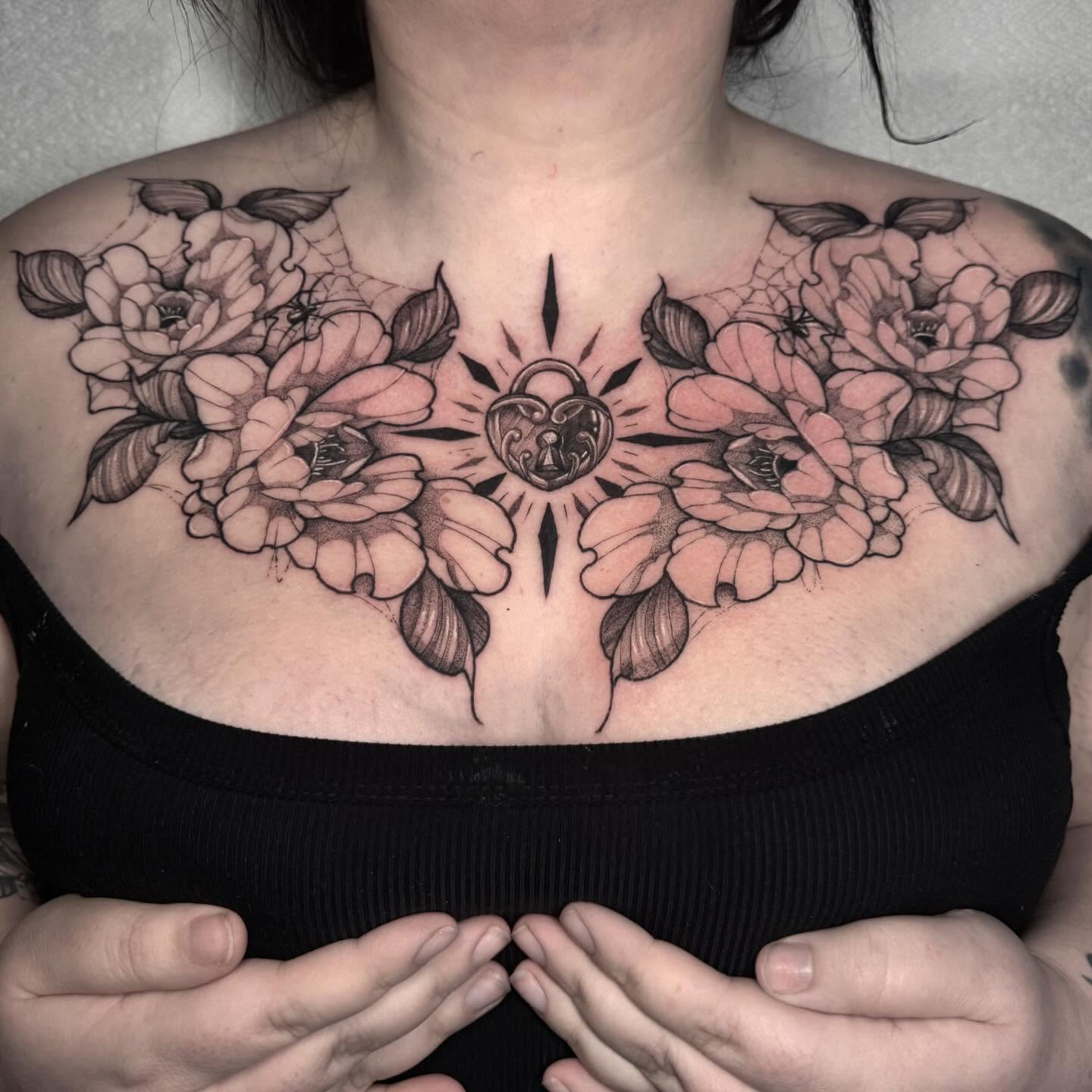 Floral arrangement with heart black and grey tattoo on the chest by 𝔈𝔯𝔦𝔫 𝔊𝔦𝔩𝔩𝔦𝔩𝔞𝔫𝔡, Springfield, Ohio