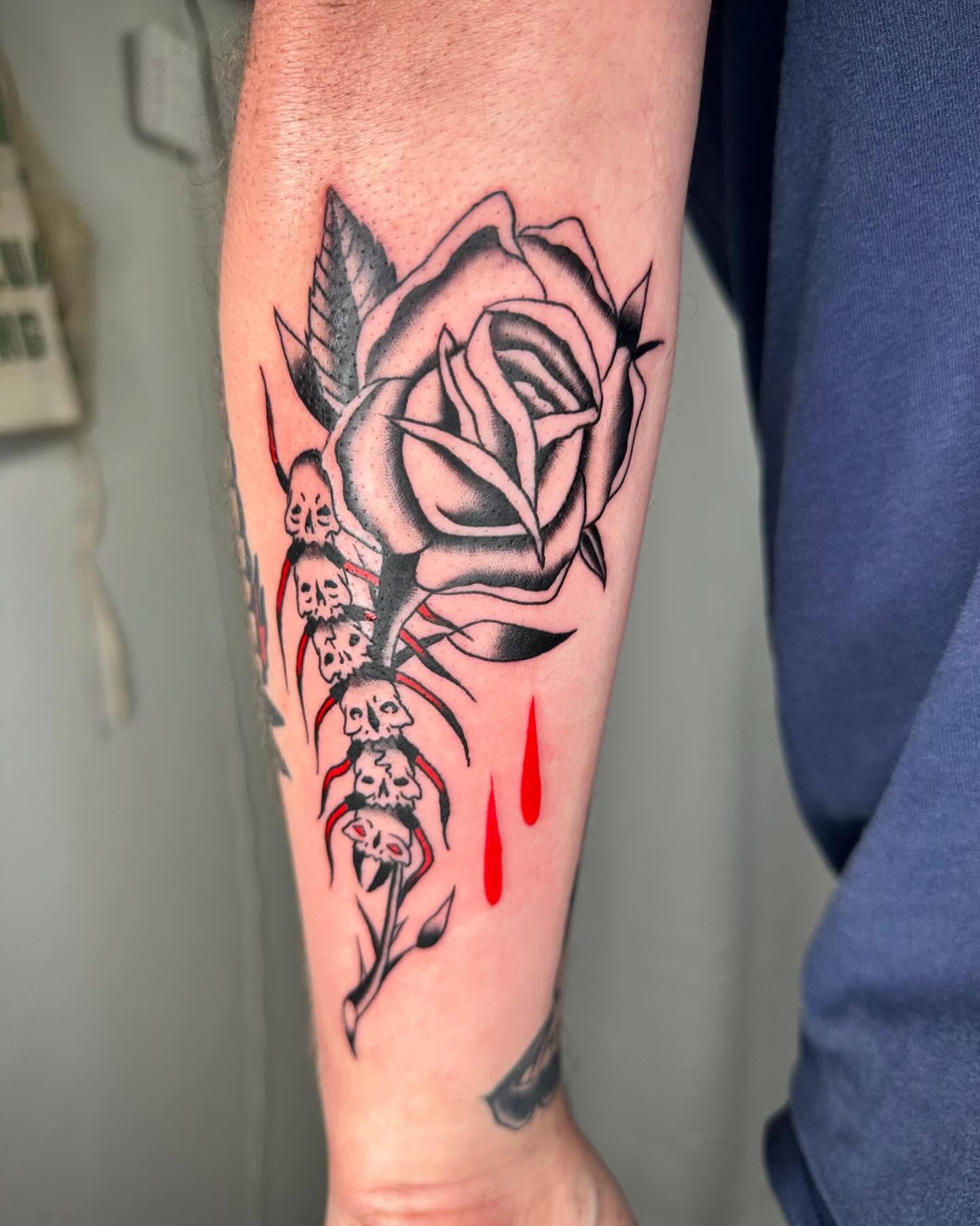 Rose with skulls dark realism tattoo on the forearm by rory