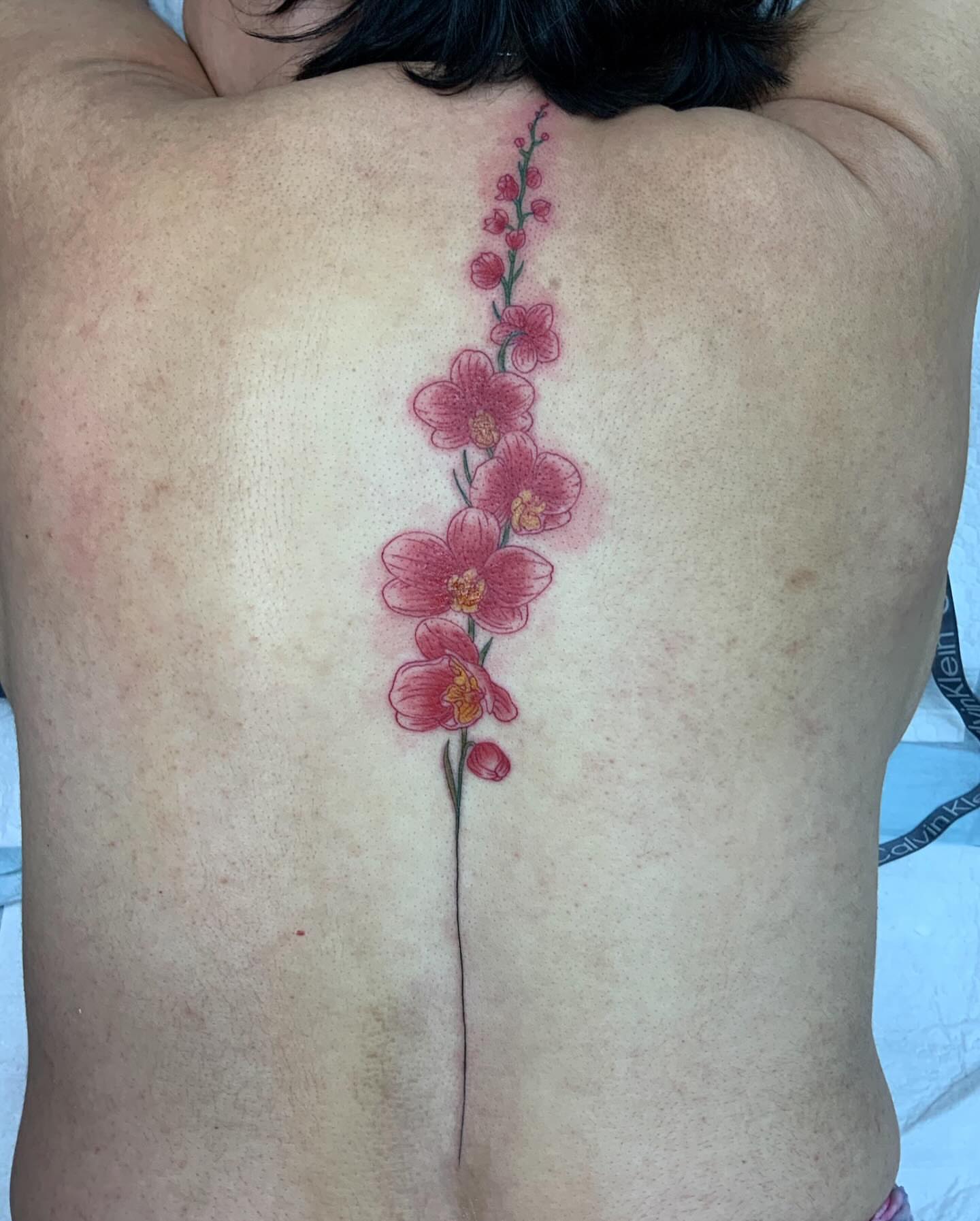 Orchid flowers new school tattoo on the back by QUEEN TATTOO Stephanie Larson