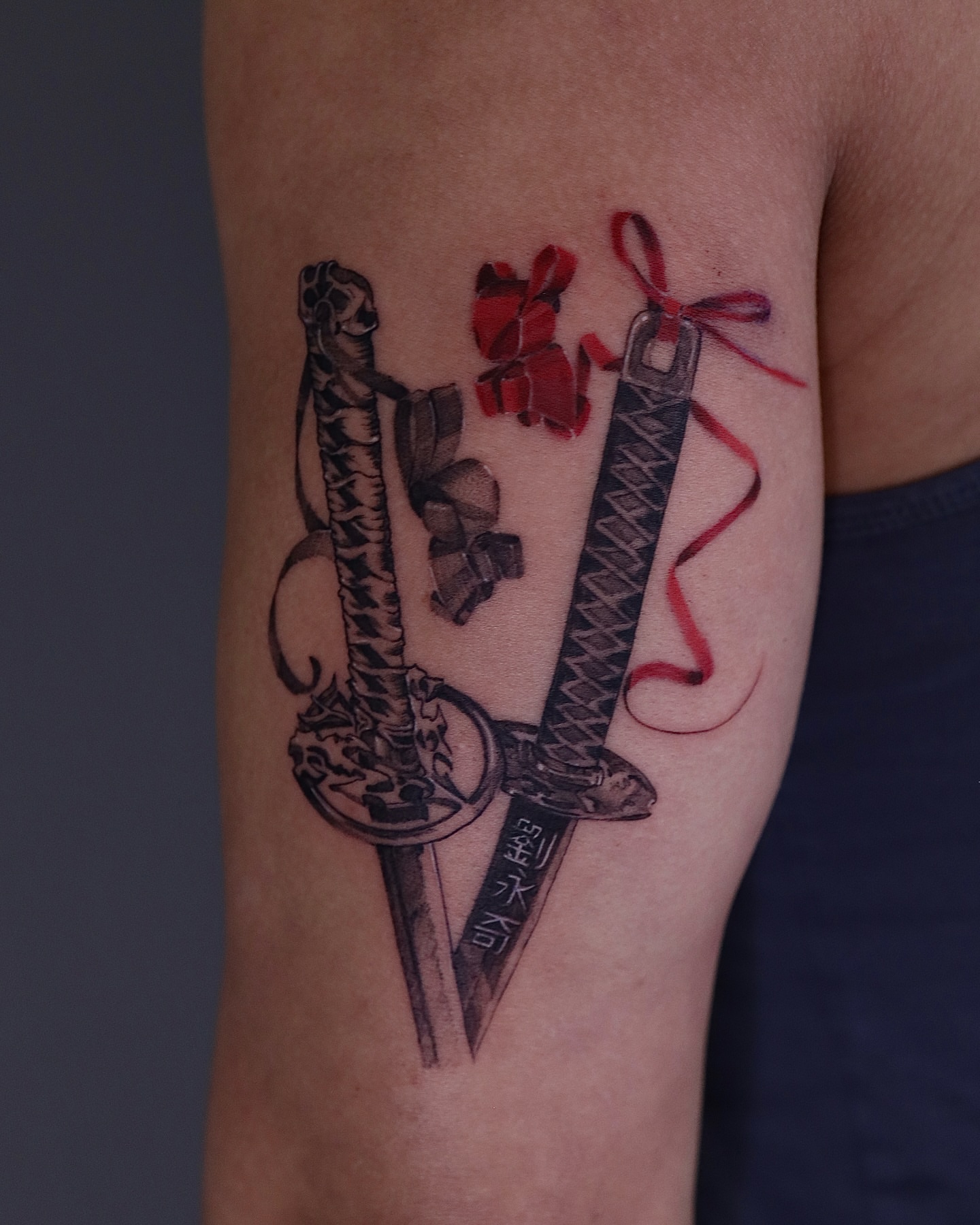 Knives and ribbon realism tattoo on the forearm by Riki