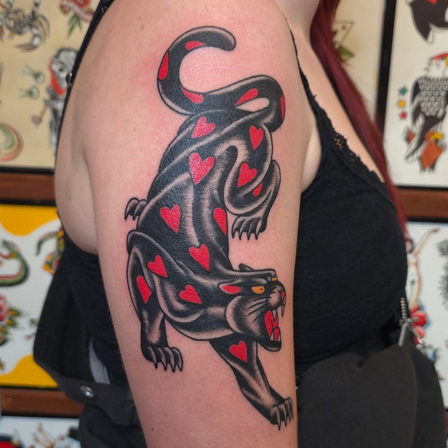Panther with hearts American traditional tattoo on the upper arm by Jared Green