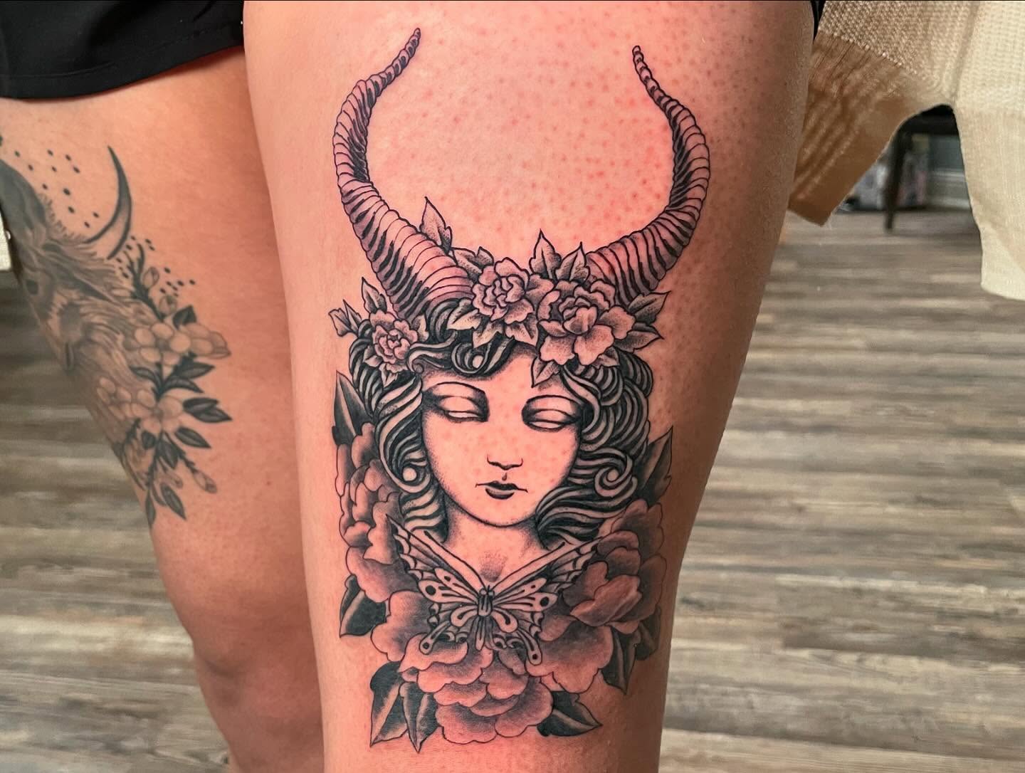 Woman with horns and flowers neo-traditional tattoo on the thigh by Caleb Baker