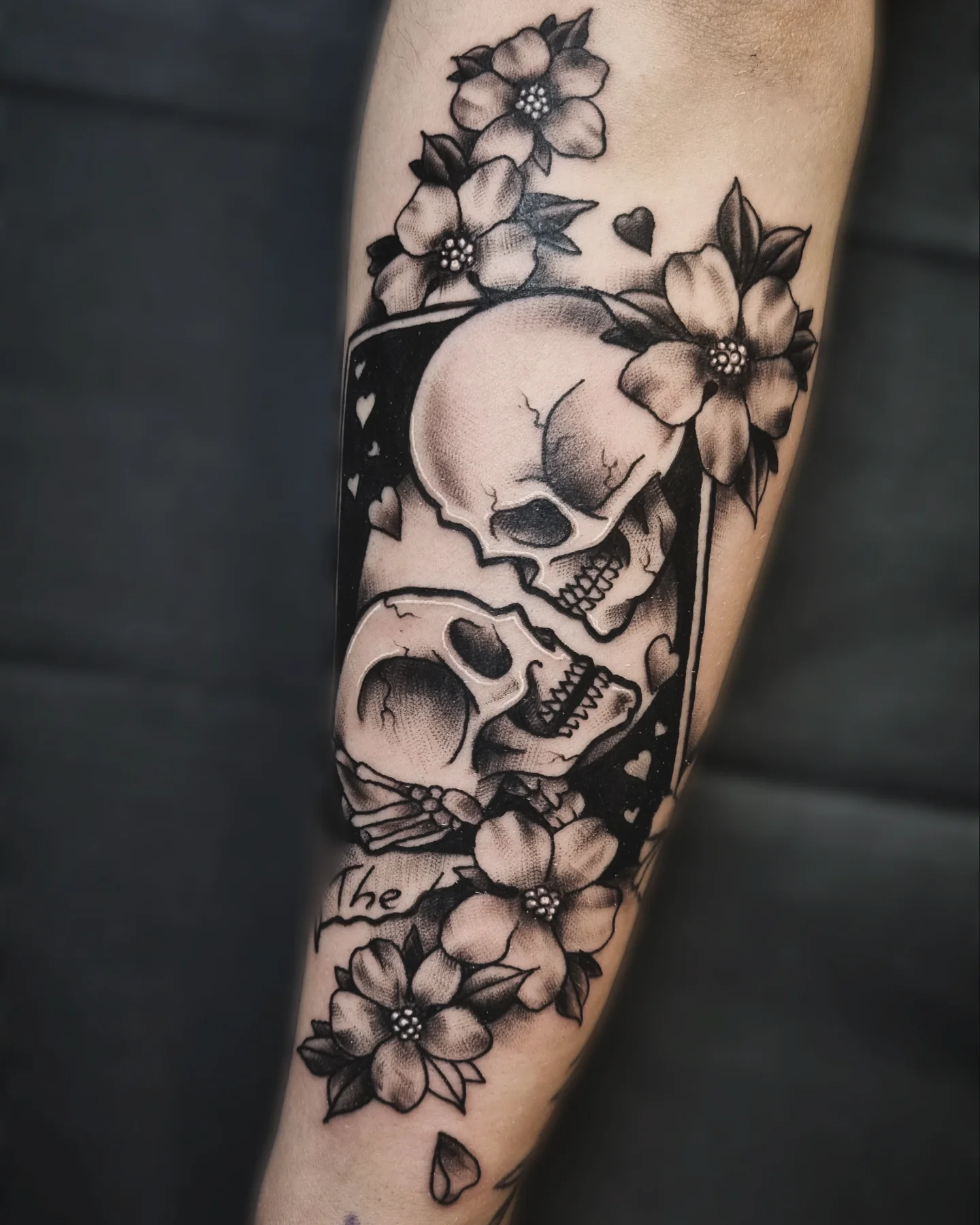 Skulls and flowers black and grey tattoo on the forearm by AntiheroTattoo