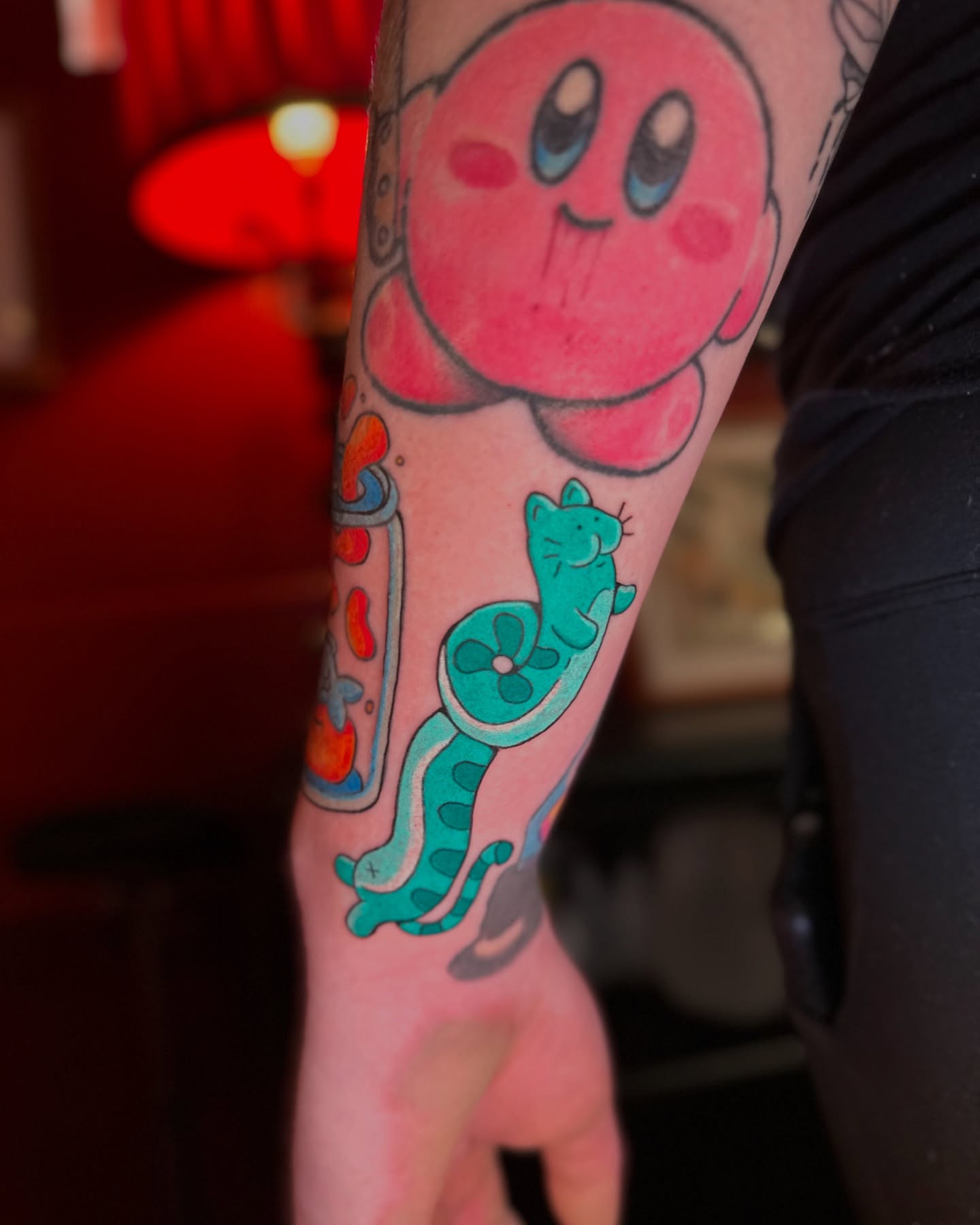 Kirby and cat new school tattoo on the forearm by Kellie Burch