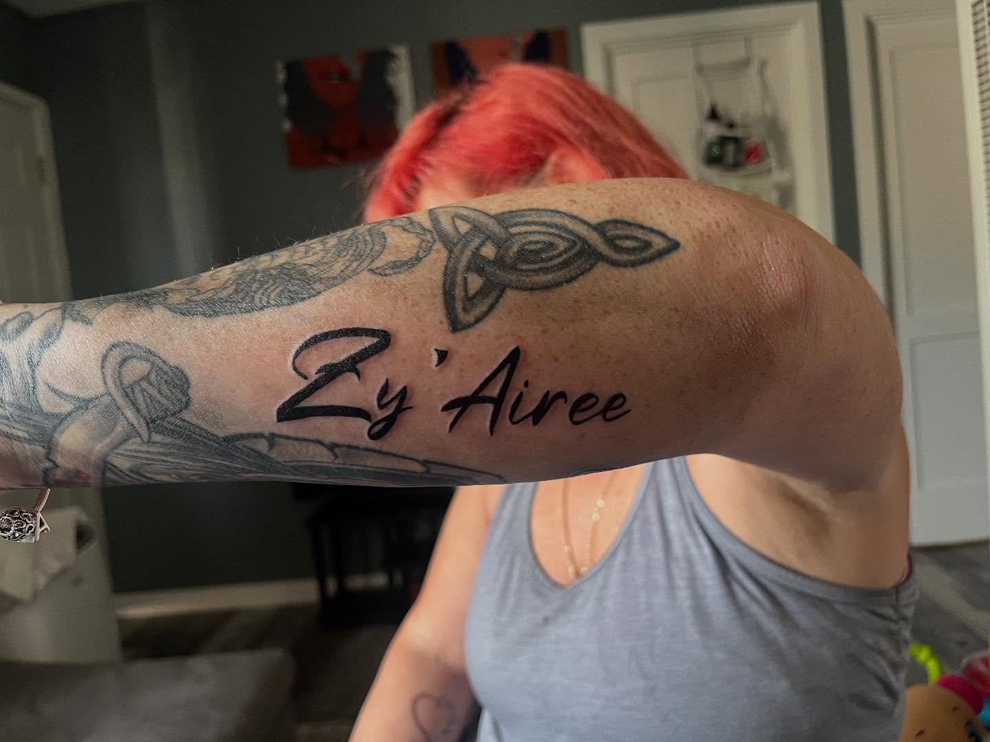 Trinity knot and cursive name black and grey tattoo on the forearm by Bris