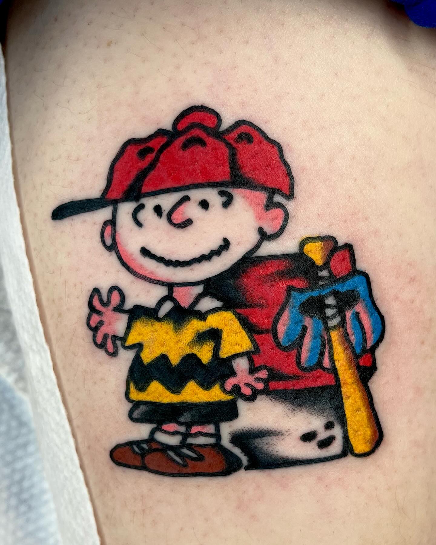Charlie Brown illustrative tattoo on the upper arm by Jimmy Ho