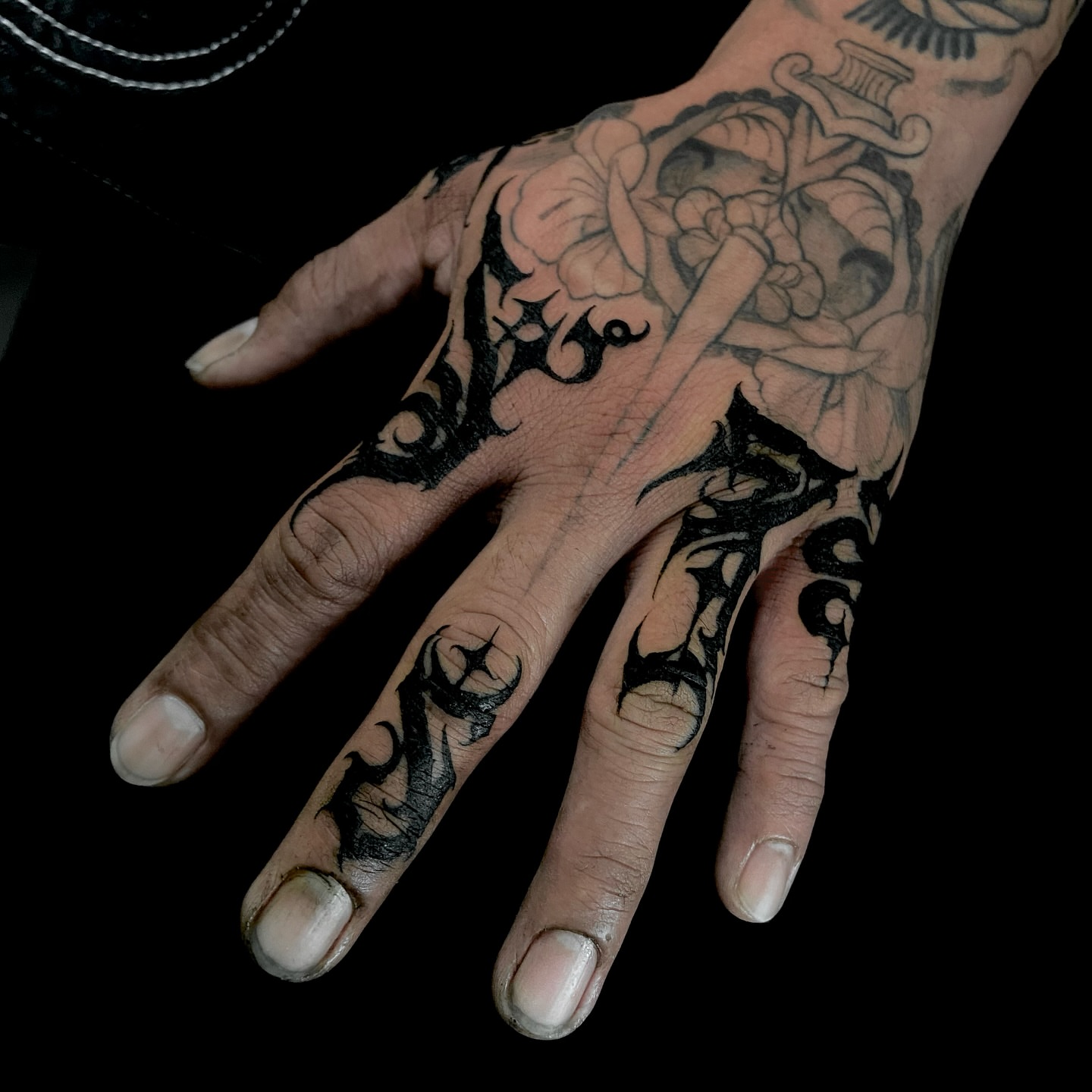 Floral arrangement black and grey tattoo on the hand by Nathan