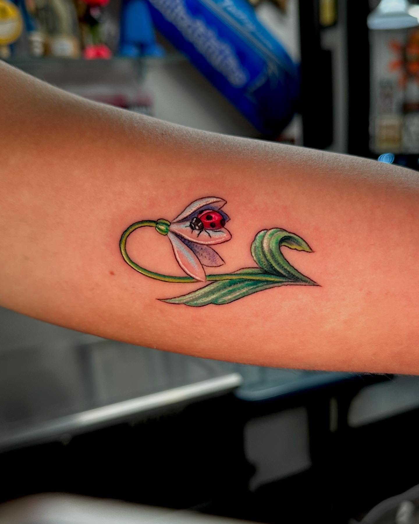 Ladybug and flower realism tattoo on the forearm by MR