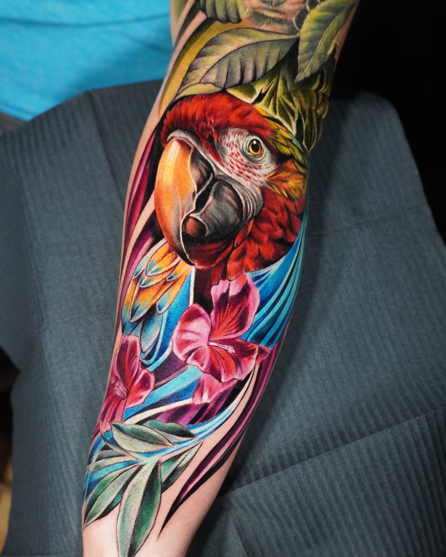 Parrot and flowers realism tattoo on the forearm by Daniela Duque Tattoo