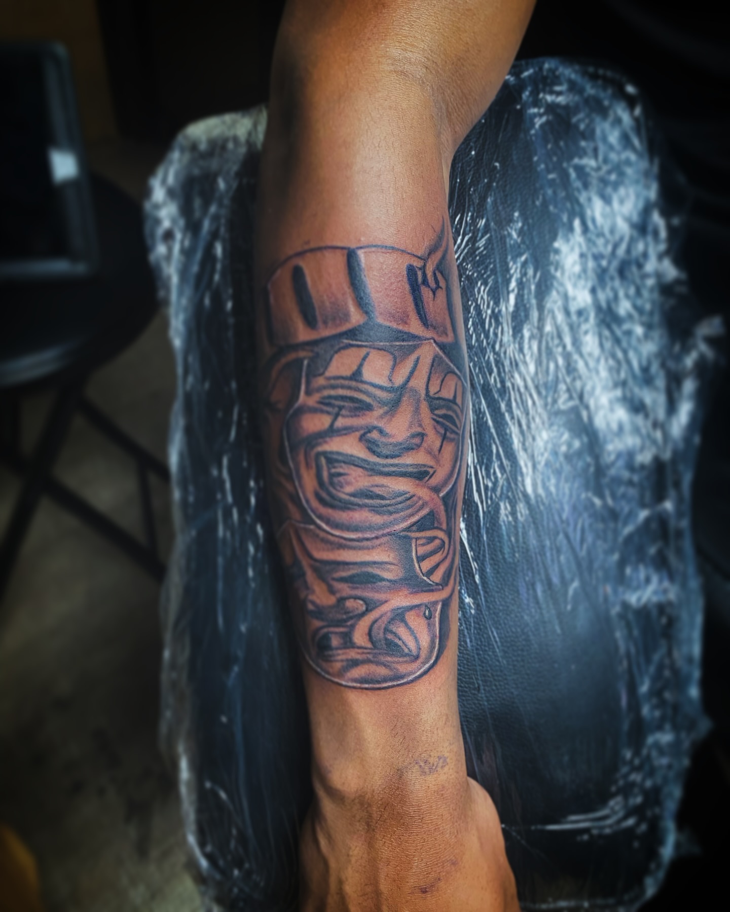 Mask black and grey tattoo on the forearm by Rico Rosario