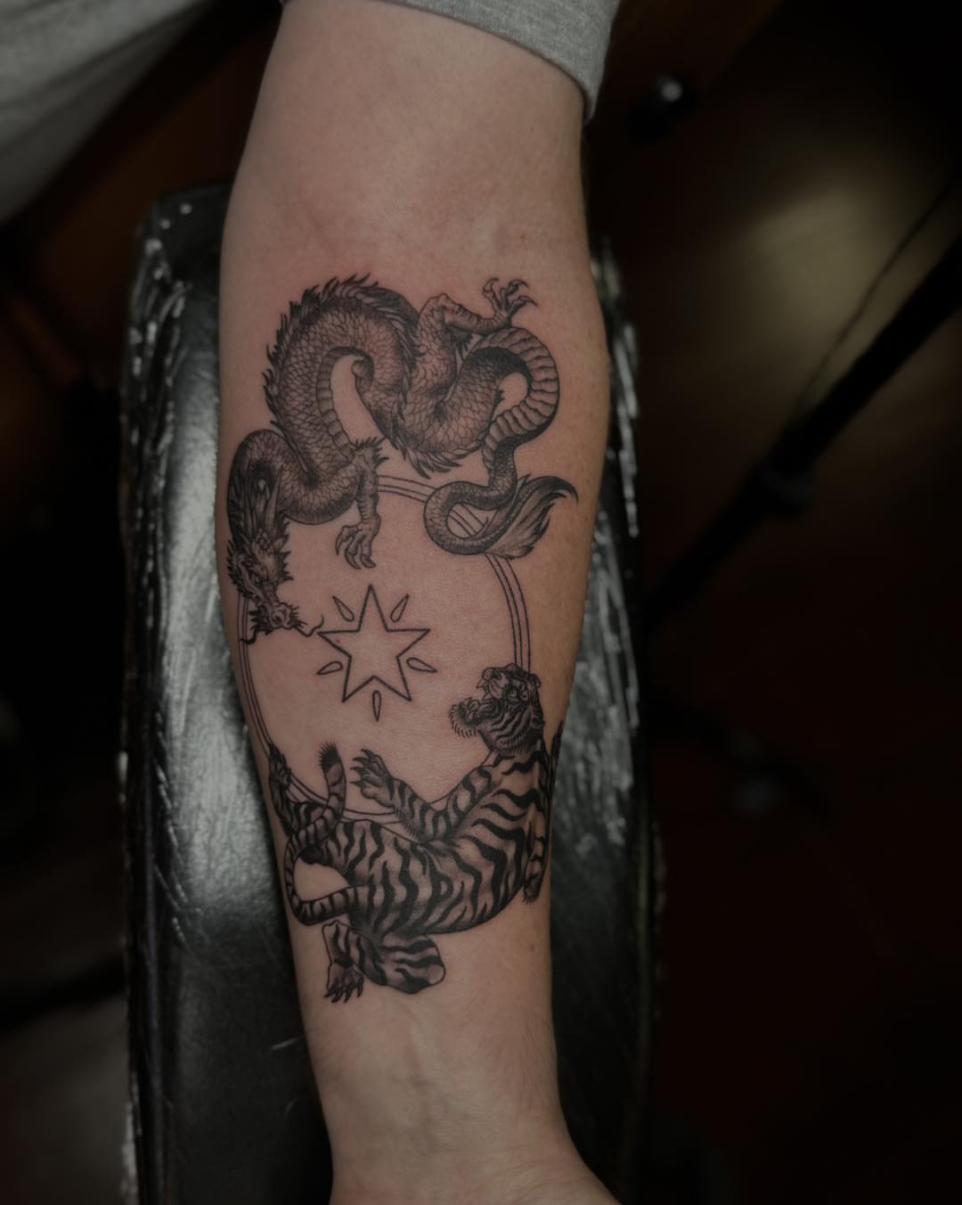 Dragon and tiger black and grey tattoo on the forearm by James Reed Tattoo artist